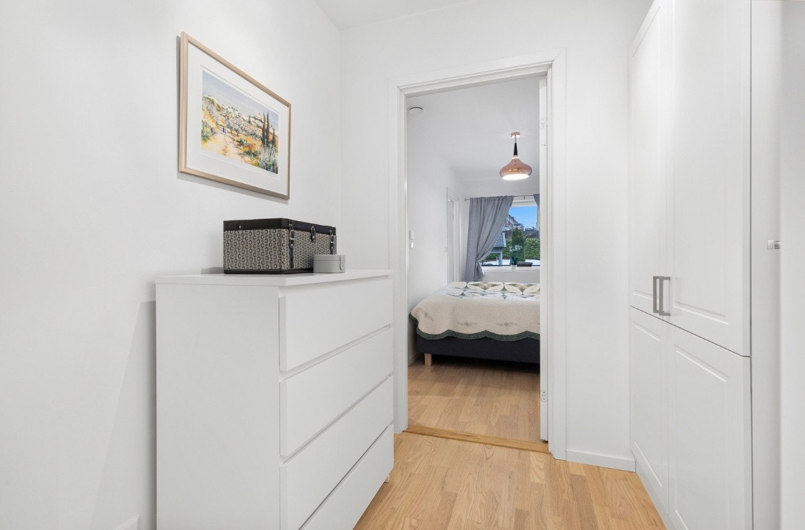 Mellom soverommet og badet i leiligheten er det et omkledningsrom med hvitt skap. Galleribilde