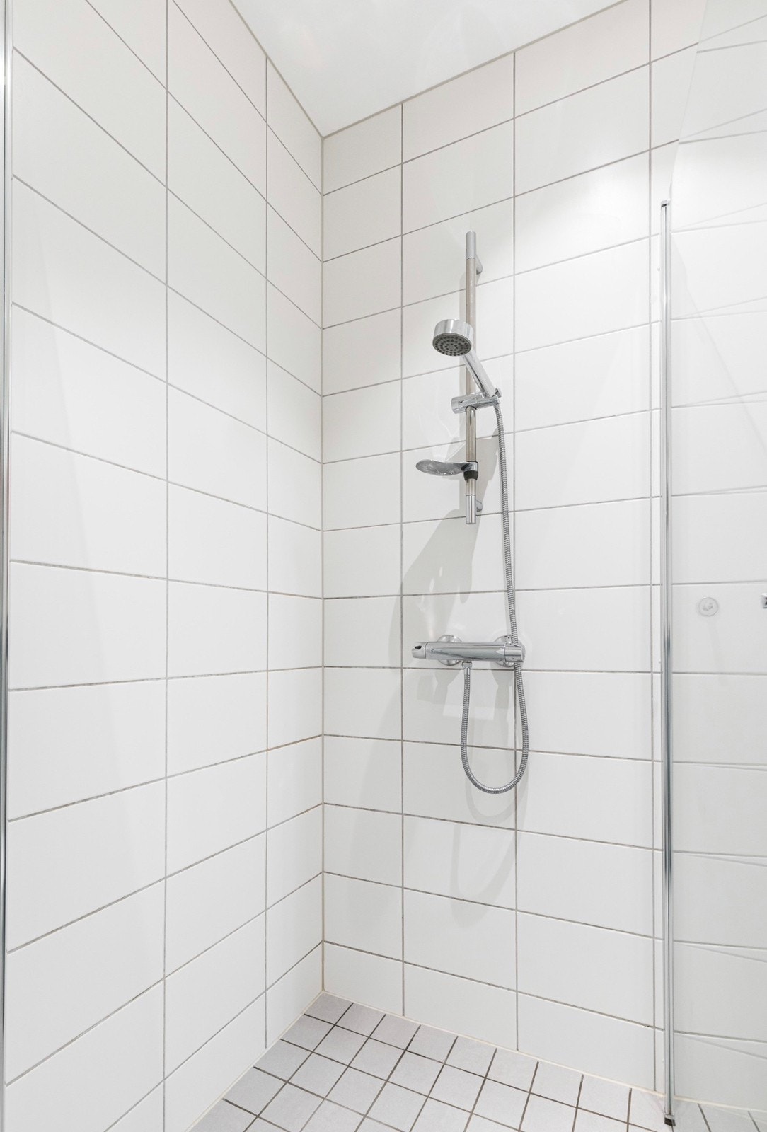 Badet har vegghengt toalett og et nedsenket dusjhjørne med innfellbare vegger. Galleribilde