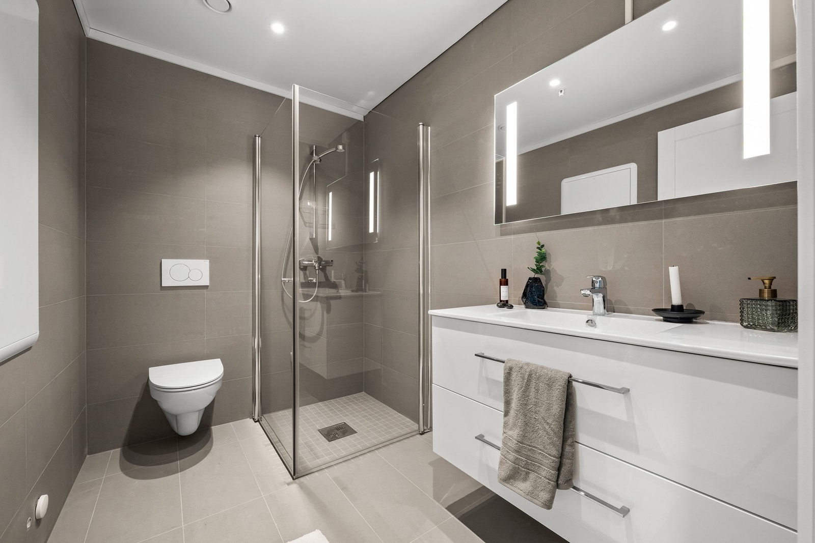 Moderne bad 1 i 2. etg med fliser på gulv og vegger. Servant i innredningen og dusjhjørne. Galleribilde