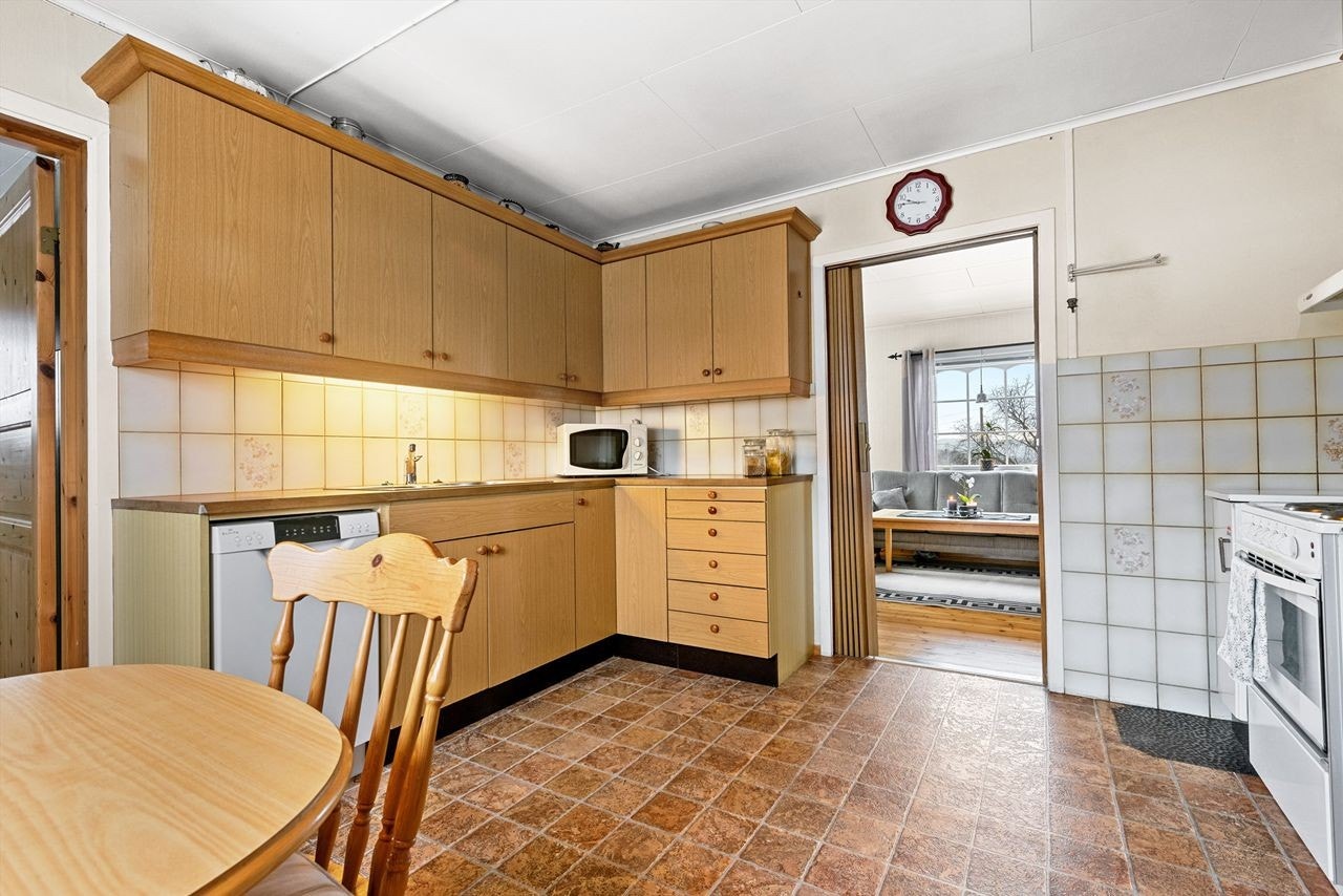 Kjøkkenet har glatte laminerte fronter i over og underskap. Laminert benkeplate og fliser i benkerygg og mot stekeovnen. Galleribilde