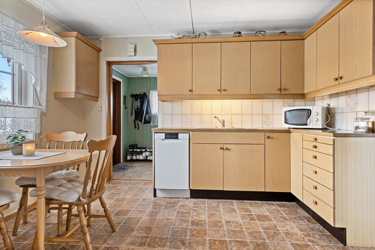 Kjøkkenet har i tillegg åpning for en smal oppvaskmaskin, stekeovn. Samt et spisemøblement. Galleribilde