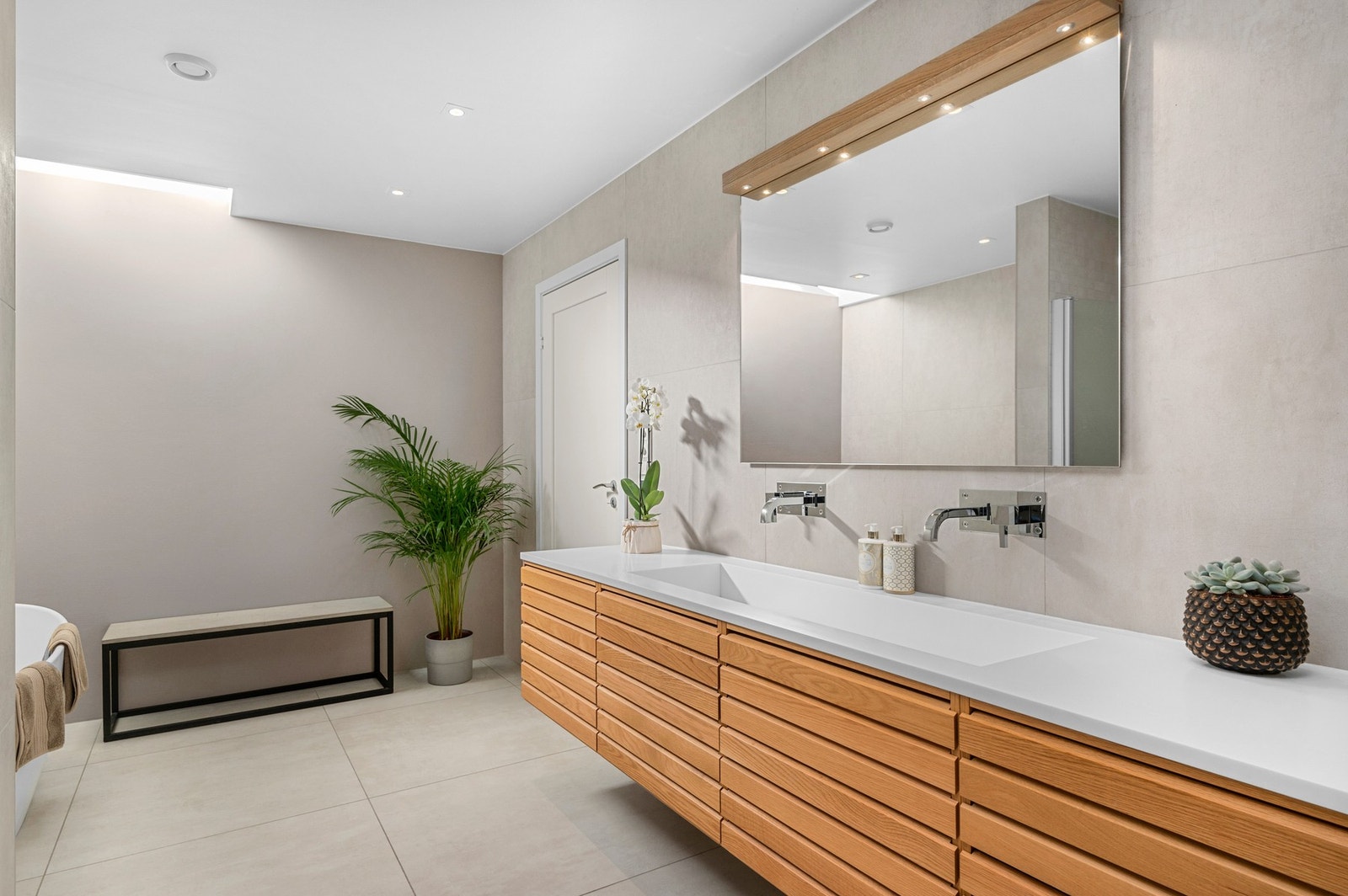 Dette eksklusive badet har en unik detalj som slipper inn rikelig med naturlig lys. Taket har en forhøyning med et vindu som er strategisk plassert for å slippe inn naturlig overlys. Galleribilde