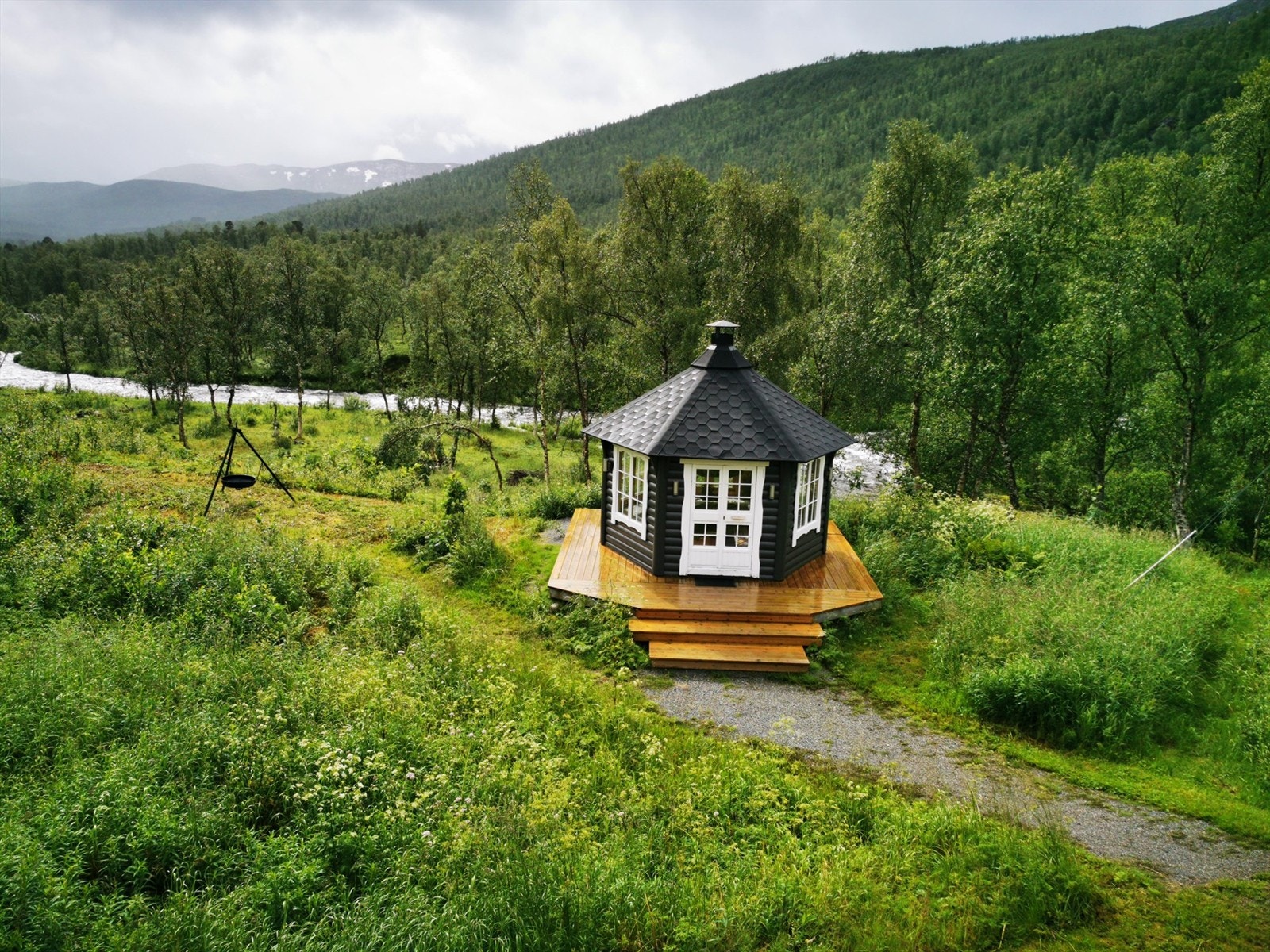 Grillhytte med platt rundt på nedsiden av hytta. Galleribilde