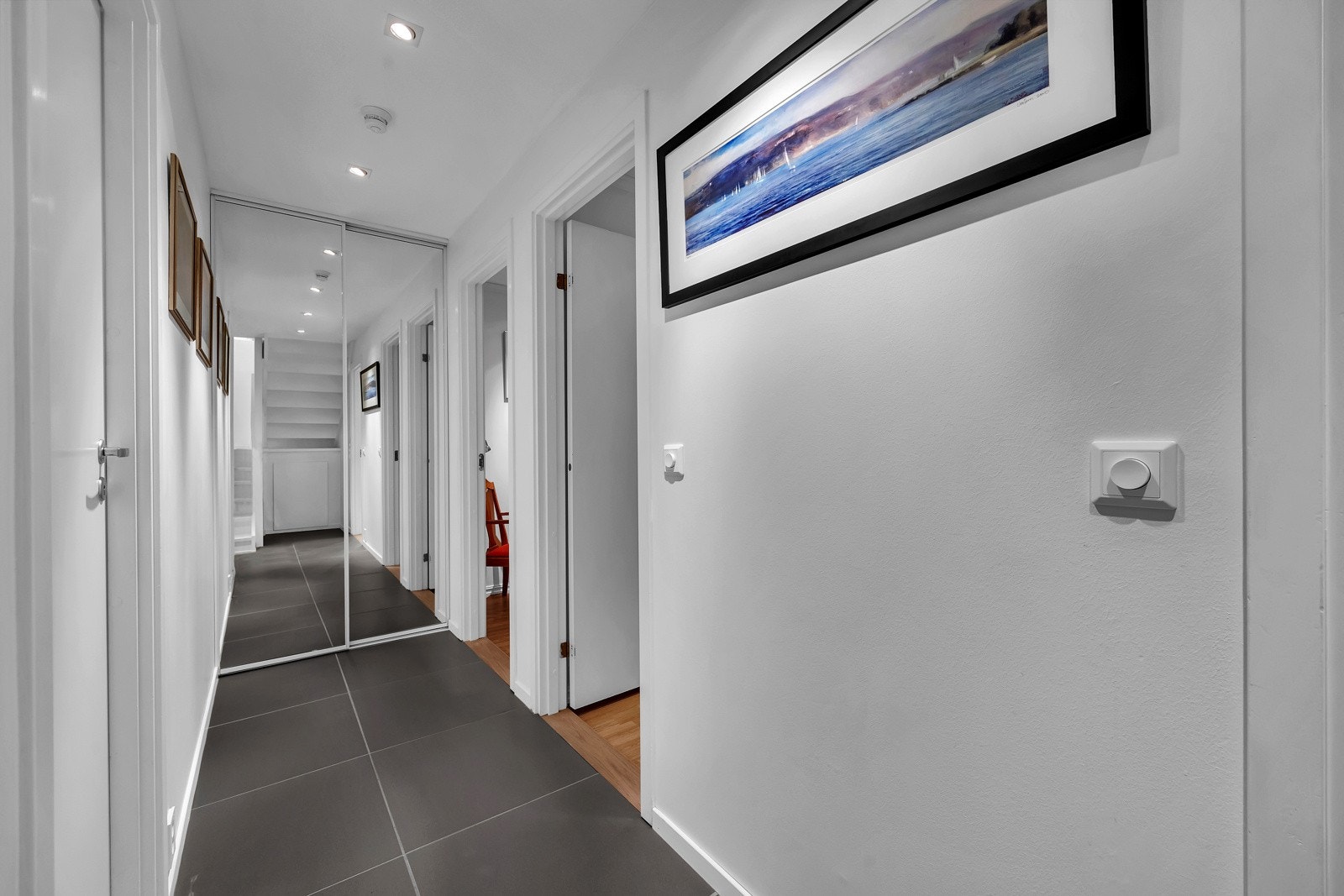 I gangen utenfor soverommene er det en stor skyvedørsgarderobe med speilfronter, som byr på godt med oppbevaringsplass til klær og tekstiler. Galleribilde