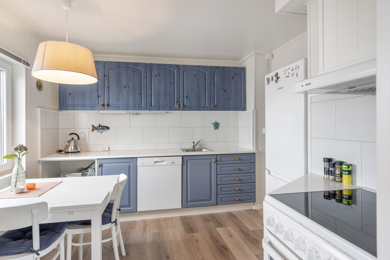 Vask i benkeplate, ventilator over komfyrplass, opplegg for oppvaskmaskin og fliser på vegg mellom over og underskap. Galleribilde