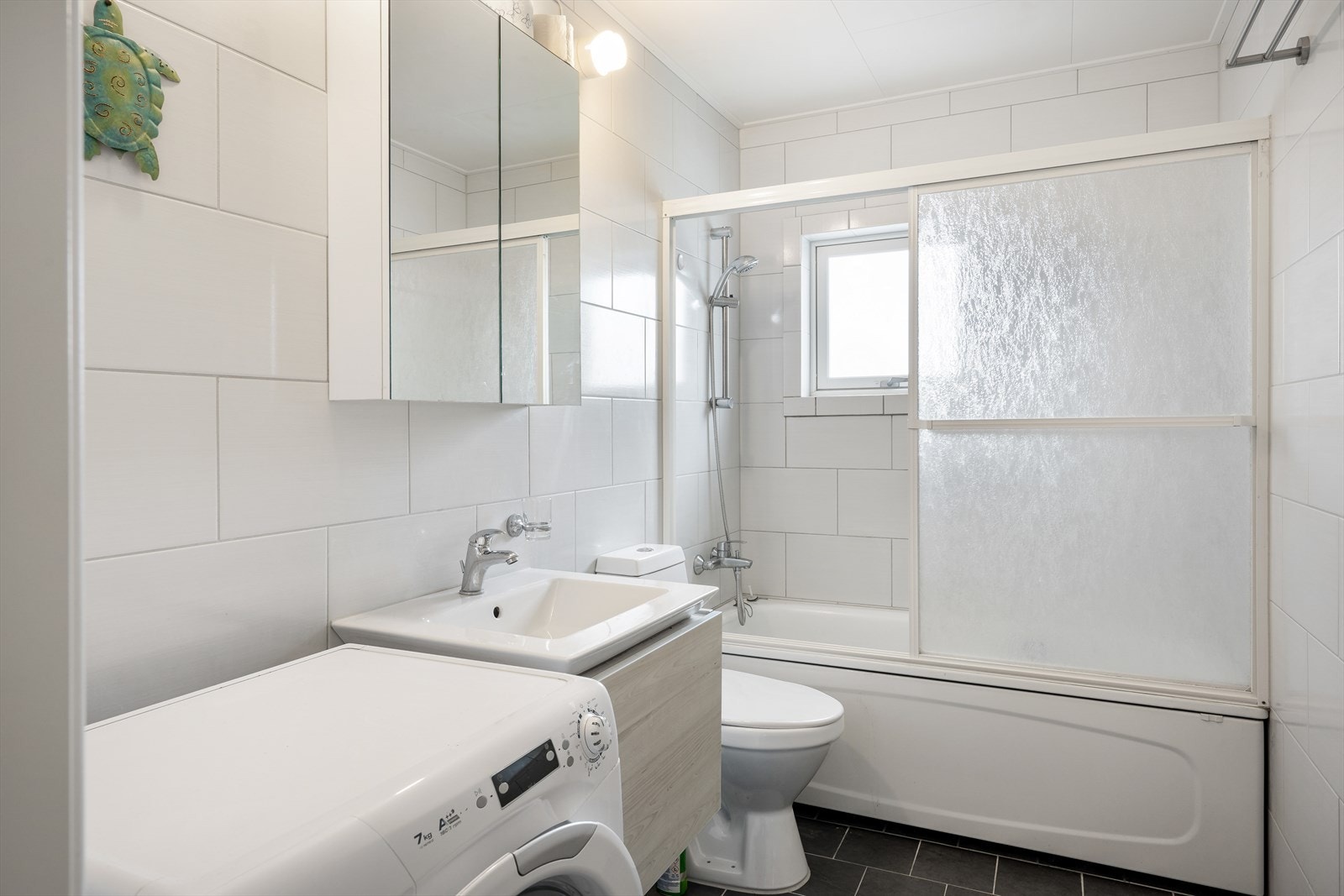 Bad 2; her er det også flis og varme i gulv. Montert innredning, et toalett, badekar og opplegg for vaskemaskin. Galleribilde