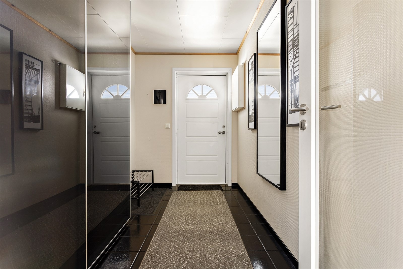 Romslig og stilig entrè med svartmalte fliser og en stor skyvedørsgarderobe. Ved inngangspartiet disponrer leiligheten en utvending bod på ca. 4.5 m2. Galleribilde