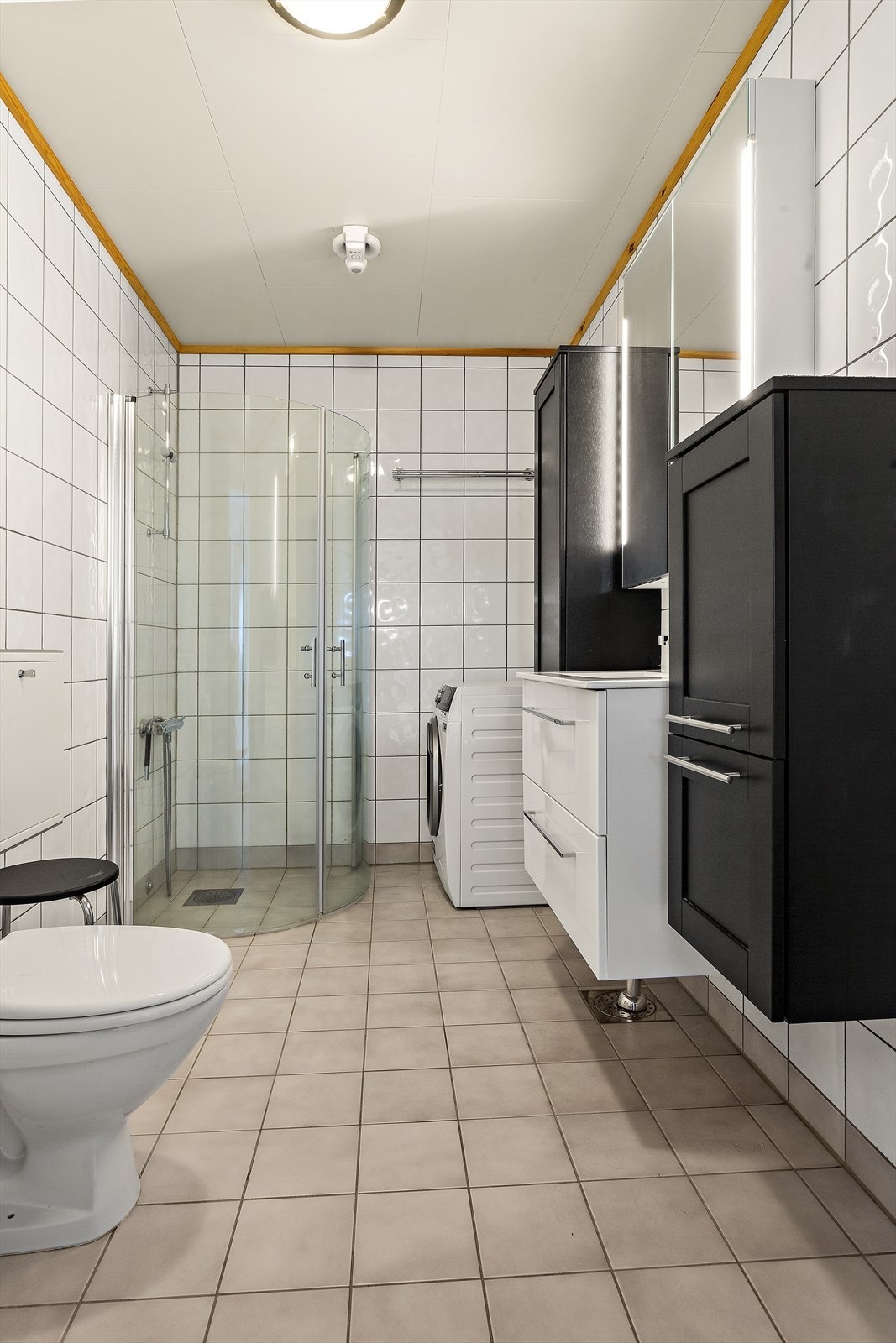 Enkelt og stilrent baderom med fliser på både vegg og gulv. Varmvannsbereder er fra 2021 og avtrekksviften er fra ca. 2019. Galleribilde