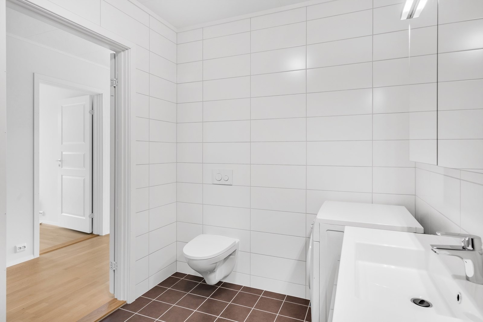 Flislagt bad hvor det er montert dusjkabinett, vegghengt toalett med innebygget sisterne og opplegg for vaskemaskin. Galleribilde