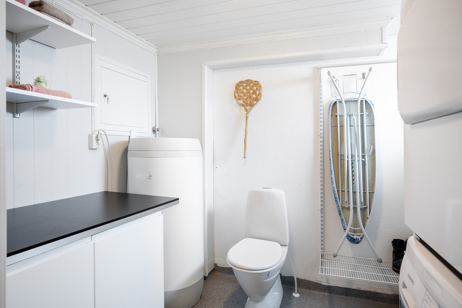Vaskerommet i underetasjen, støpt gulv med belegg. Her er det montert et toalett, skyllekar, opplegg for vaskemaskin og noe innredning. Galleribilde
