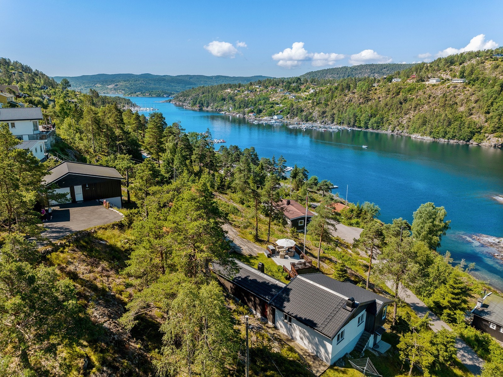 Bilvei frem med parkering i garasje og på gårdsplass. Trappeadkomst fra garasje til fritidsbolig Galleribilde