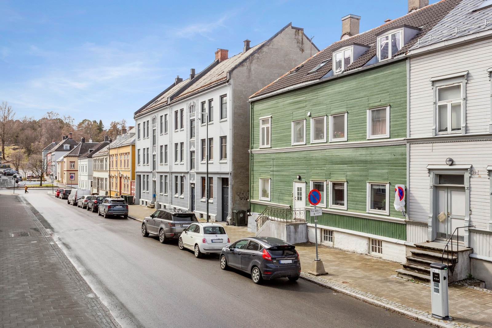 Like utenfor er det soneparkering og elbilladere. Gaten er enveiskjørt og oppleves som rolig samtidig som den har en pen beleggningsstein på fortauet. Galleribilde