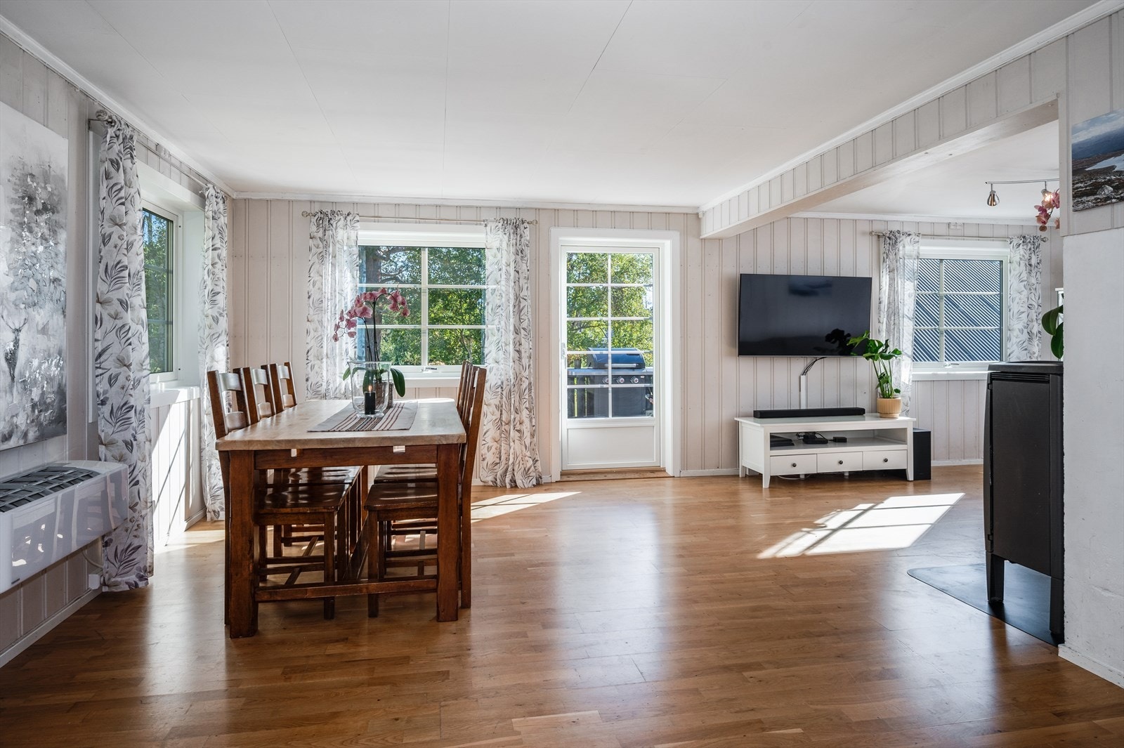 Romslig og lys stue/spisestue som består av parkett på gulv, panel på vegger og plater i himling. Galleribilde