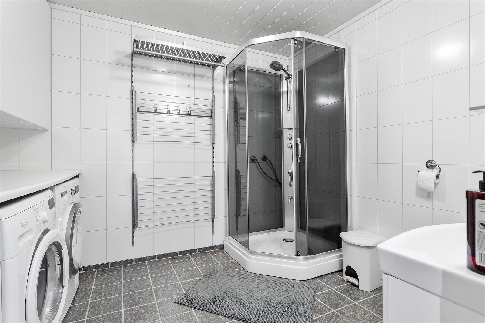Badet har praktisk vaskeromsløsning samt servant, toalett og dusjkabinett. Badet ble innredet i 2007 og har flislagte gulv med varmekabler og baderomsplater på vegg. Galleribilde