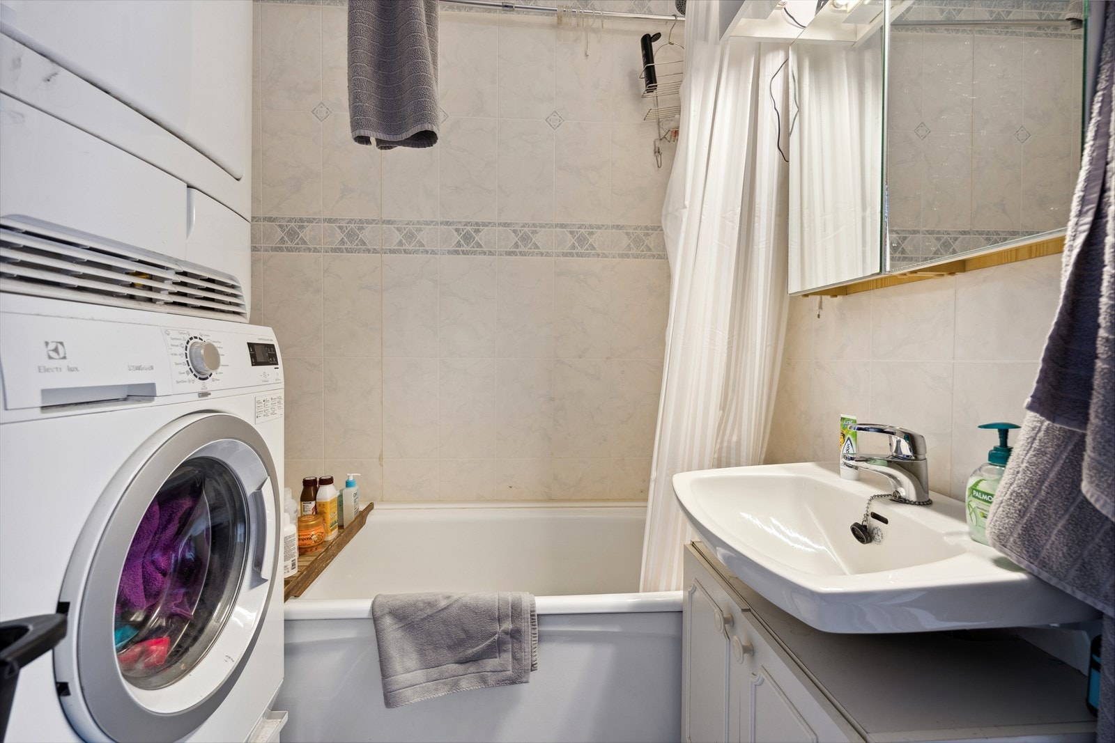 Baderom med badekar, servant, speil og opplegg for vaskemaskin. Galleribilde