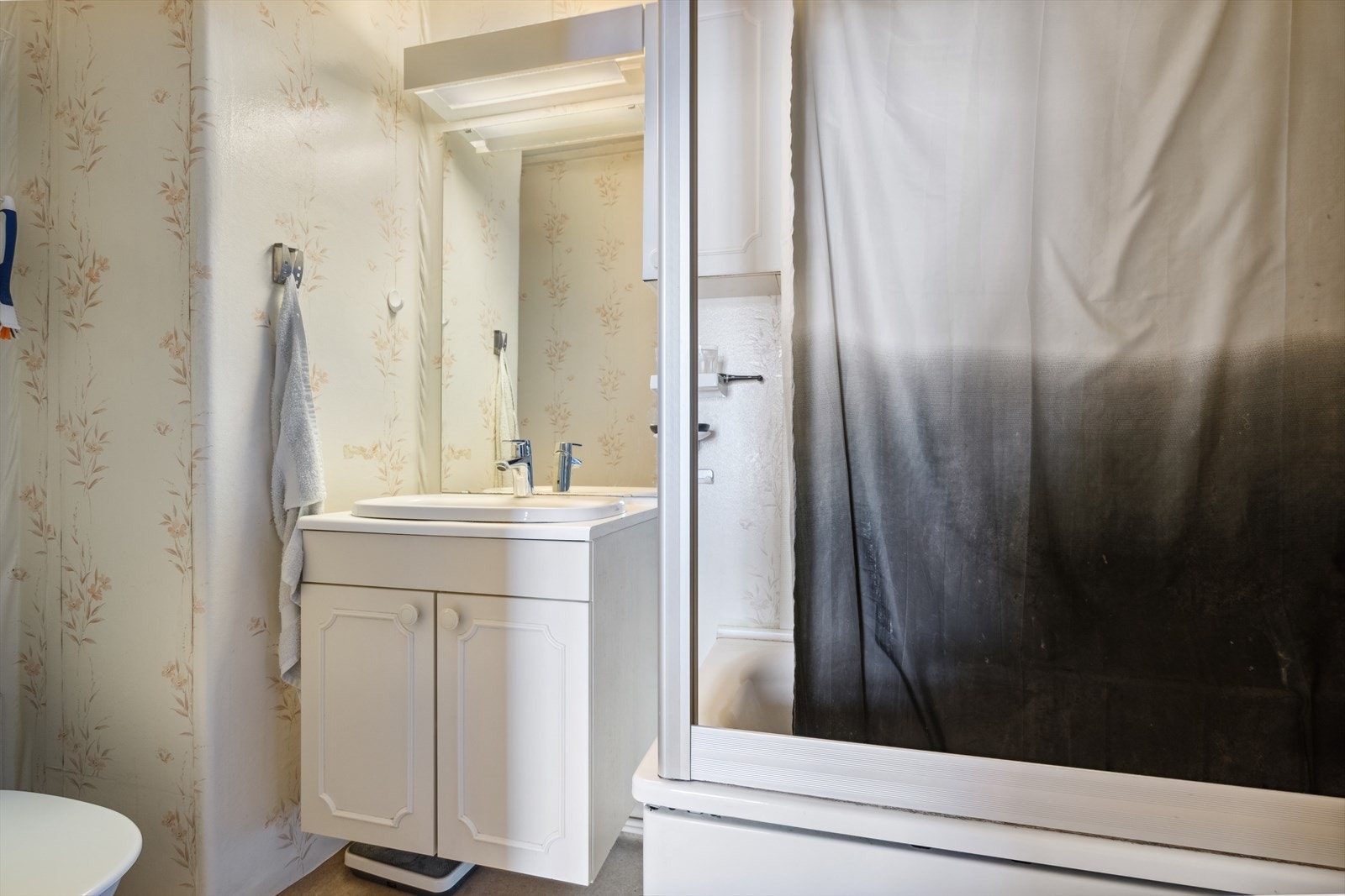 Baderommet i loftsetasjen er innredet med heldekkende servant over innredning, veggmontert speilskap med lys, badekar og opplegg for vaskemaskin. Galleribilde