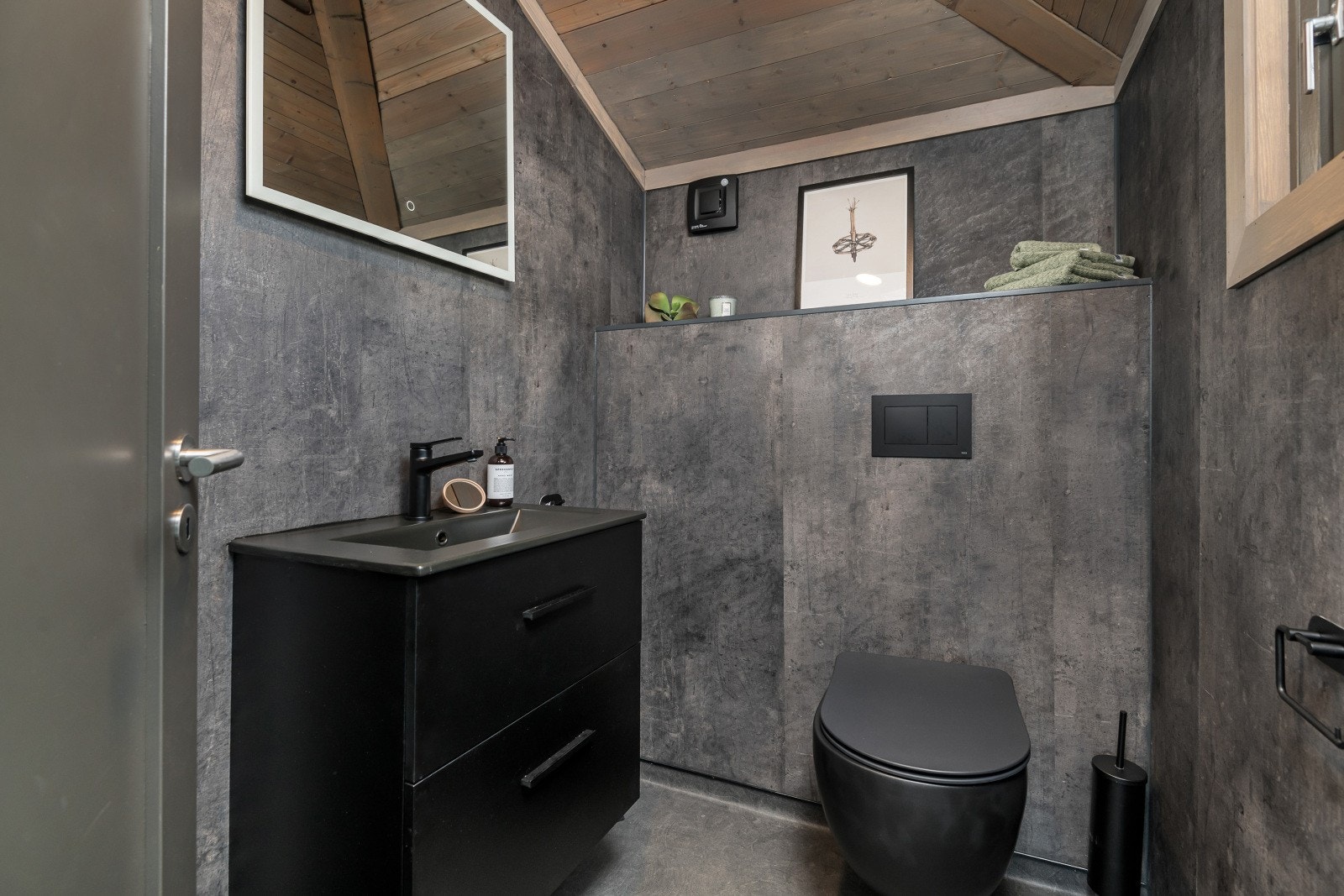 Ved entreen er det adkomst til et praktisk toalettrom og et vaskerom. Toalettrommet inneholder veggheng WC, vask med underskap og speil. Baderomsplater på vegger, panel i tak og belegg på gulv med gulvvarme. Toalettrommet fremstår som svært innbydende. Galleribilde