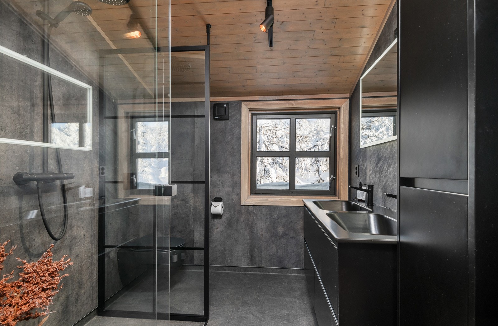 Lekkert baderom fra 2022 inneholder dobbelservant med underskap, speil med tilhørende belysning, dusjvegger, dusjnisje og vegghengt WC. Her er det baderomsplater på vegg, panel i himling og belegg på gulv med varmekabler. Galleribilde