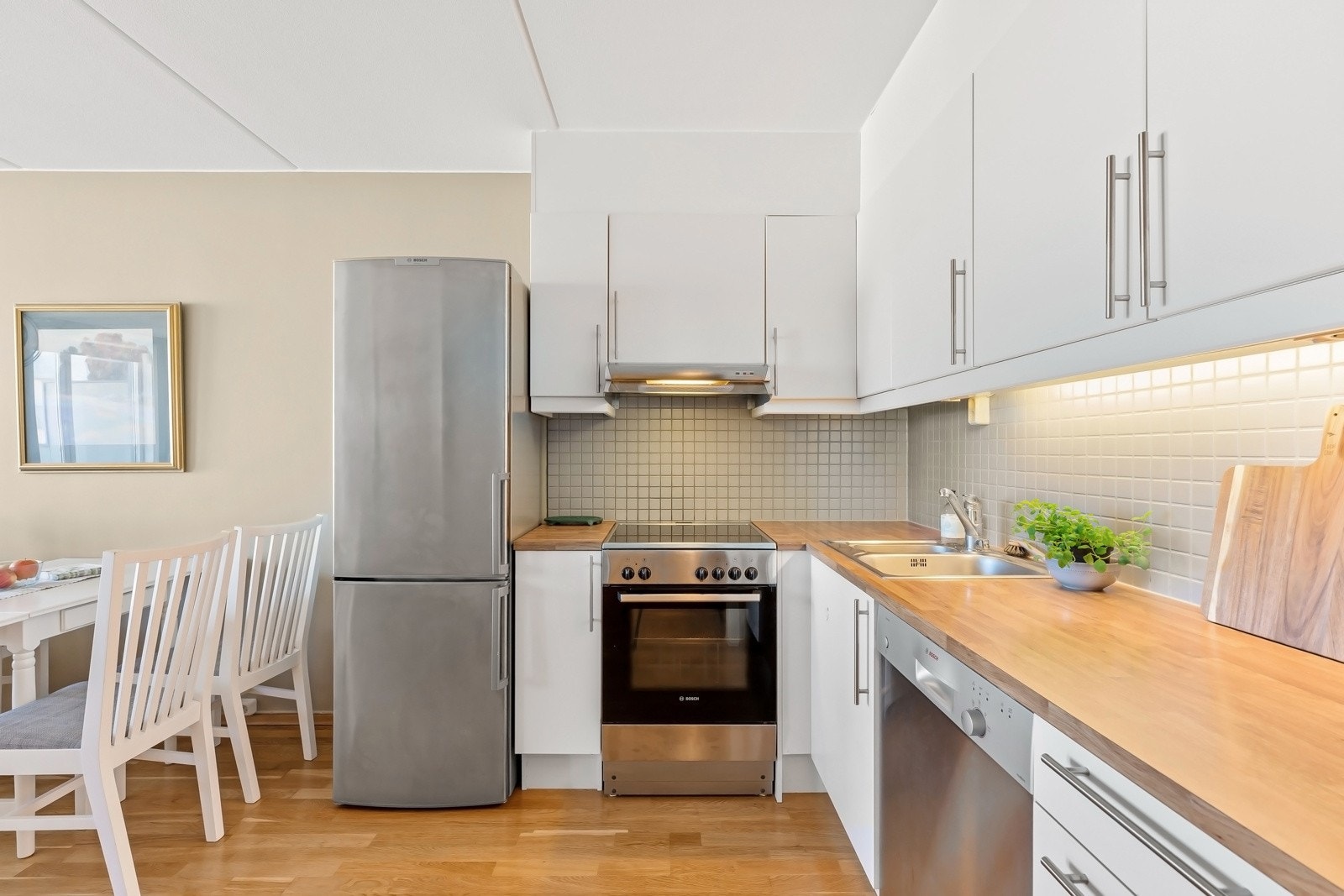 Kjøkkeninnredning med hvite glatte fronter på skuffer og over-/underskap Galleribilde