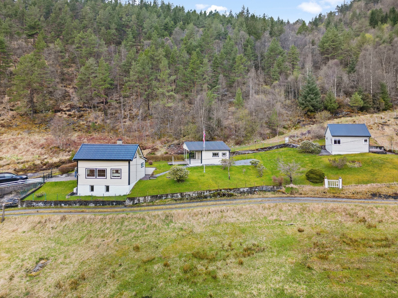 Eiendommen består av et mindre bolighus, hytte, uthus og garasje Galleribilde