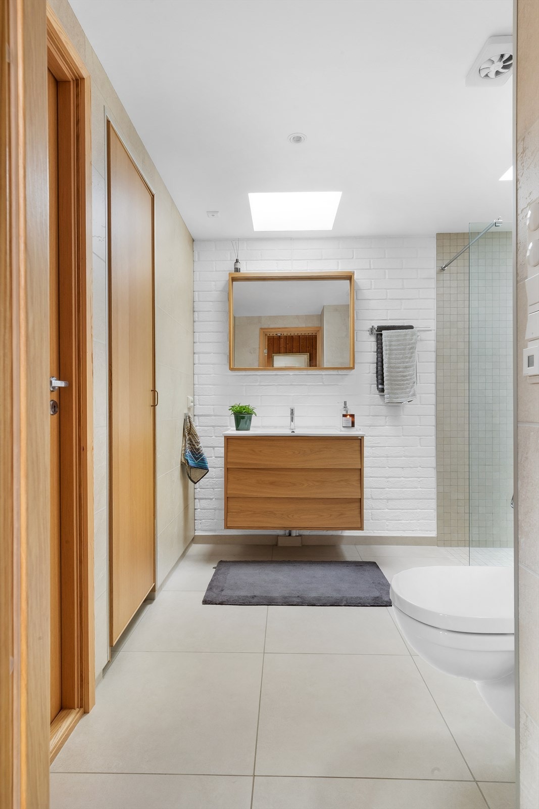 Det inneholder dusjnisje med glassvegg, vegghengt toalett og servant med underskap. Galleribilde