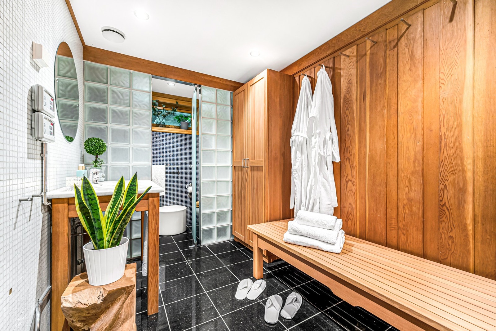 SPA-avd har Black Galaxy granitt på gulv og hvit italiensk glassmosaikk fra Bisazza med noen innlagte sølv- og gullfliser på vegger. WC og servant i Carrara marmor bak glassveggen. Skap, bord og trevegg i oregon pine heltre. Benkeplate i Carrara marmor. Galleribilde