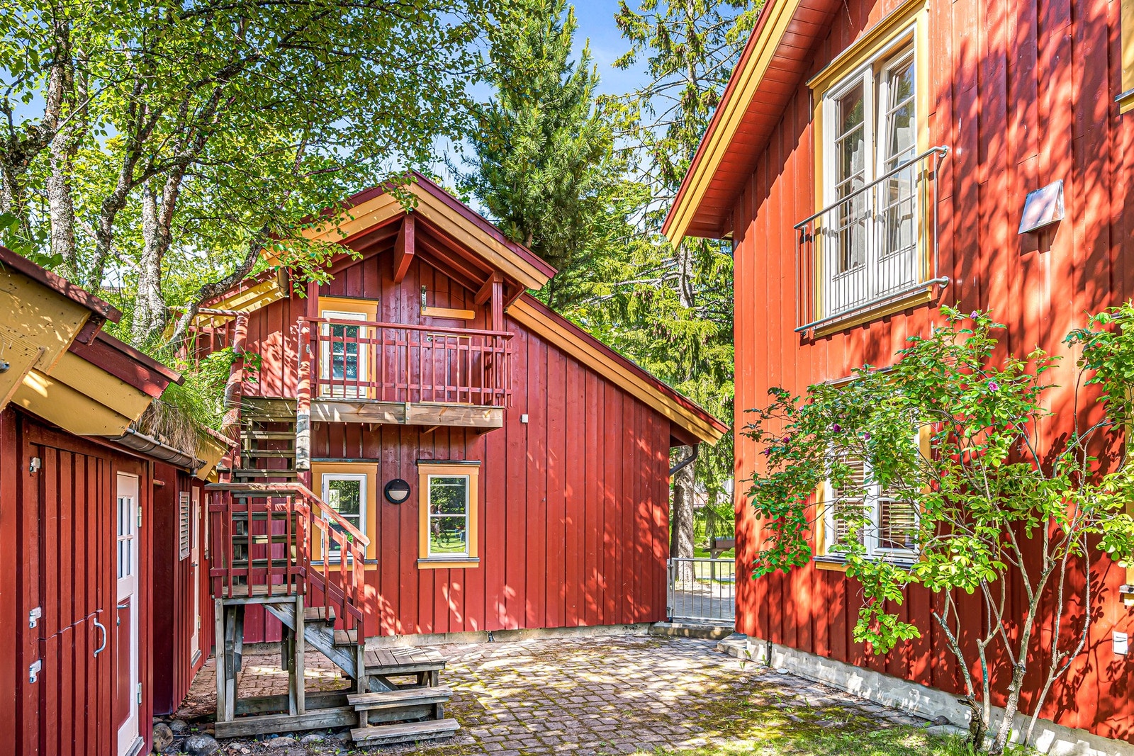 Dobbelgarasjen sett fra hagen. Den danner et atrium mellom hus og de 5 bodene. Over garasjen med trapp opp, ligger Dunken . Lavt under taket, men stor plass til lagring og/eller barnelekestue. Galleribilde