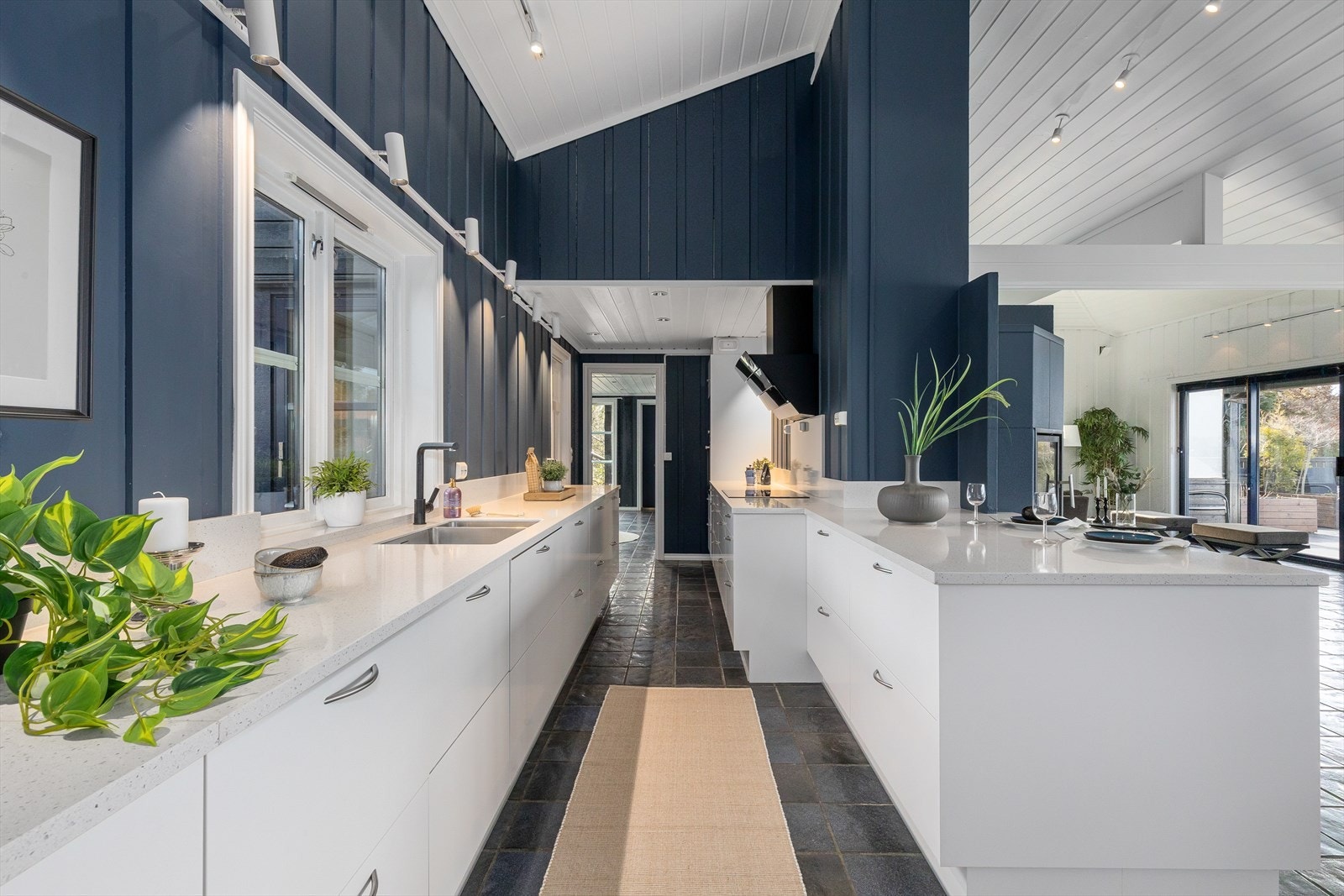 Det er gode arbeidsflater langs benkeplater i lys stein. Halvøya skaper et fint skille mot spisestuen. Galleribilde