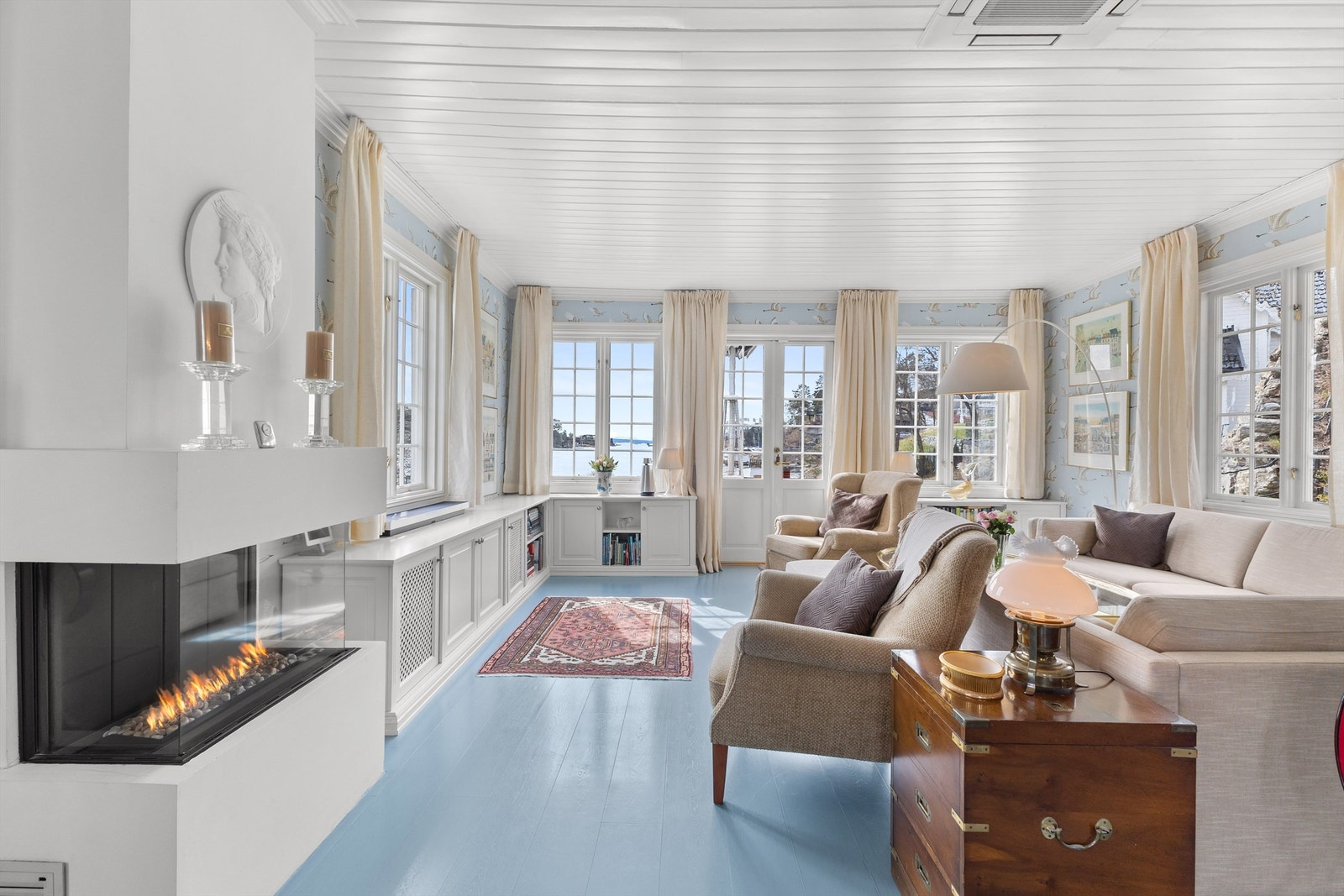 Rommet har store vindusflater, slik at du får både dagslys og Oslofjorden inn i stuen. Midt i rommet er det en stilig gasspeis. Galleribilde