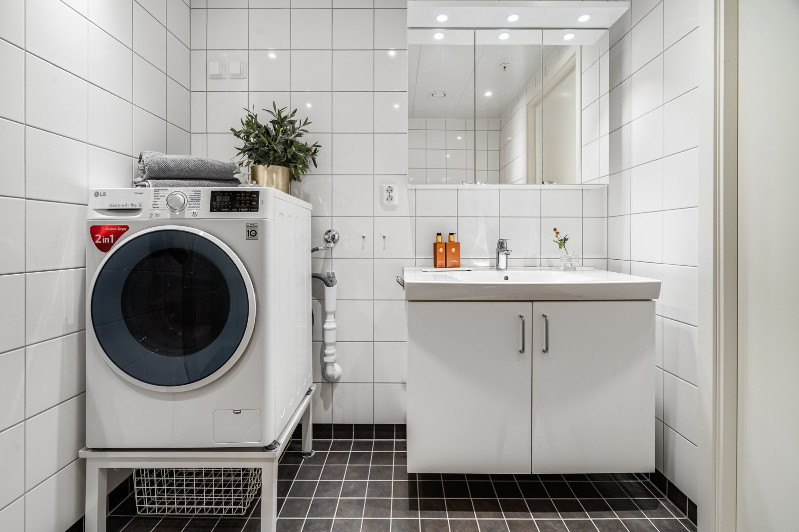 Flislagt bad med moderne baderomsinnredning og overspeil med belysning.