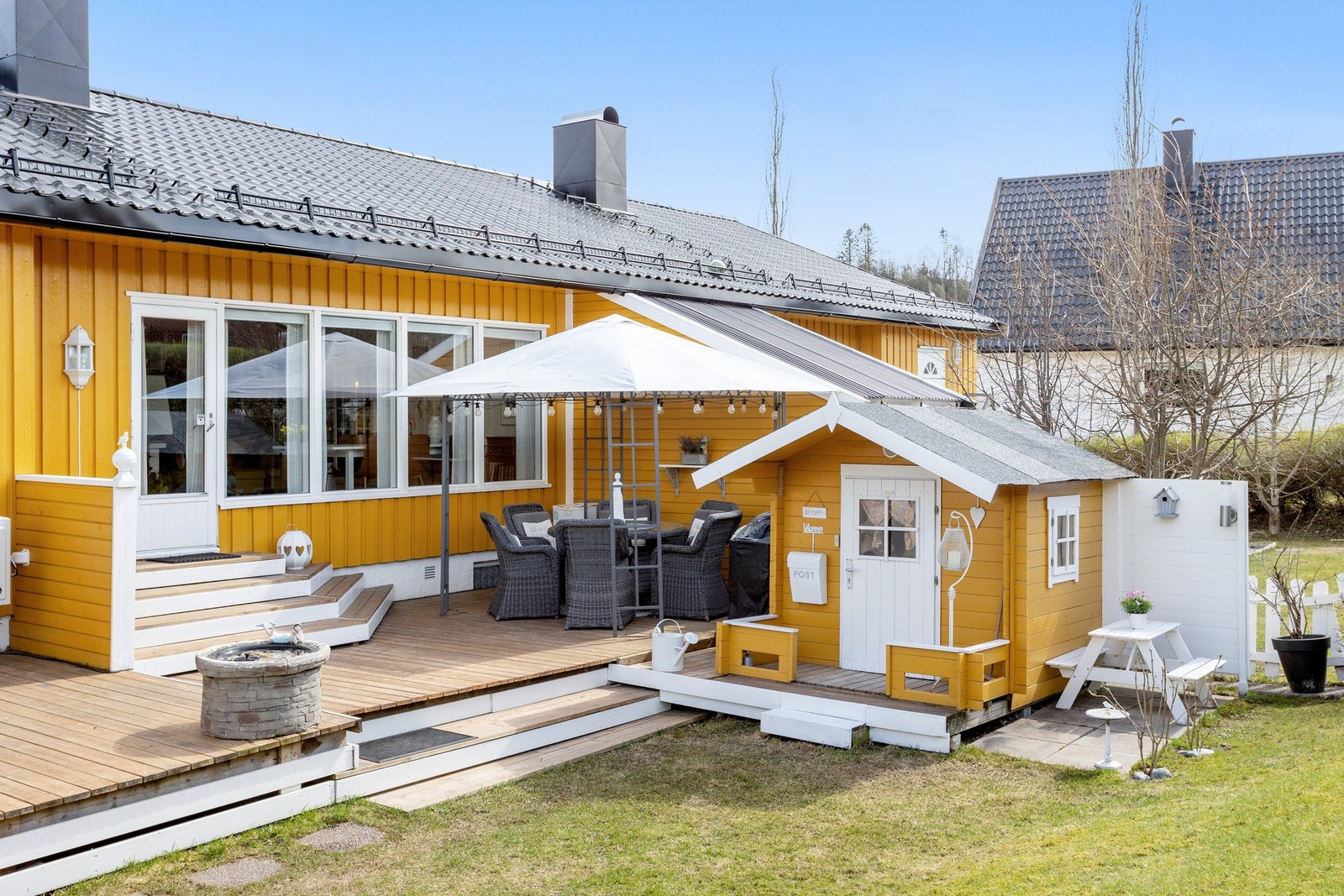 På oversiden av huset har du en meget innbydende og solrik vestvendt terrasse med hage og dokkestue Galleribilde