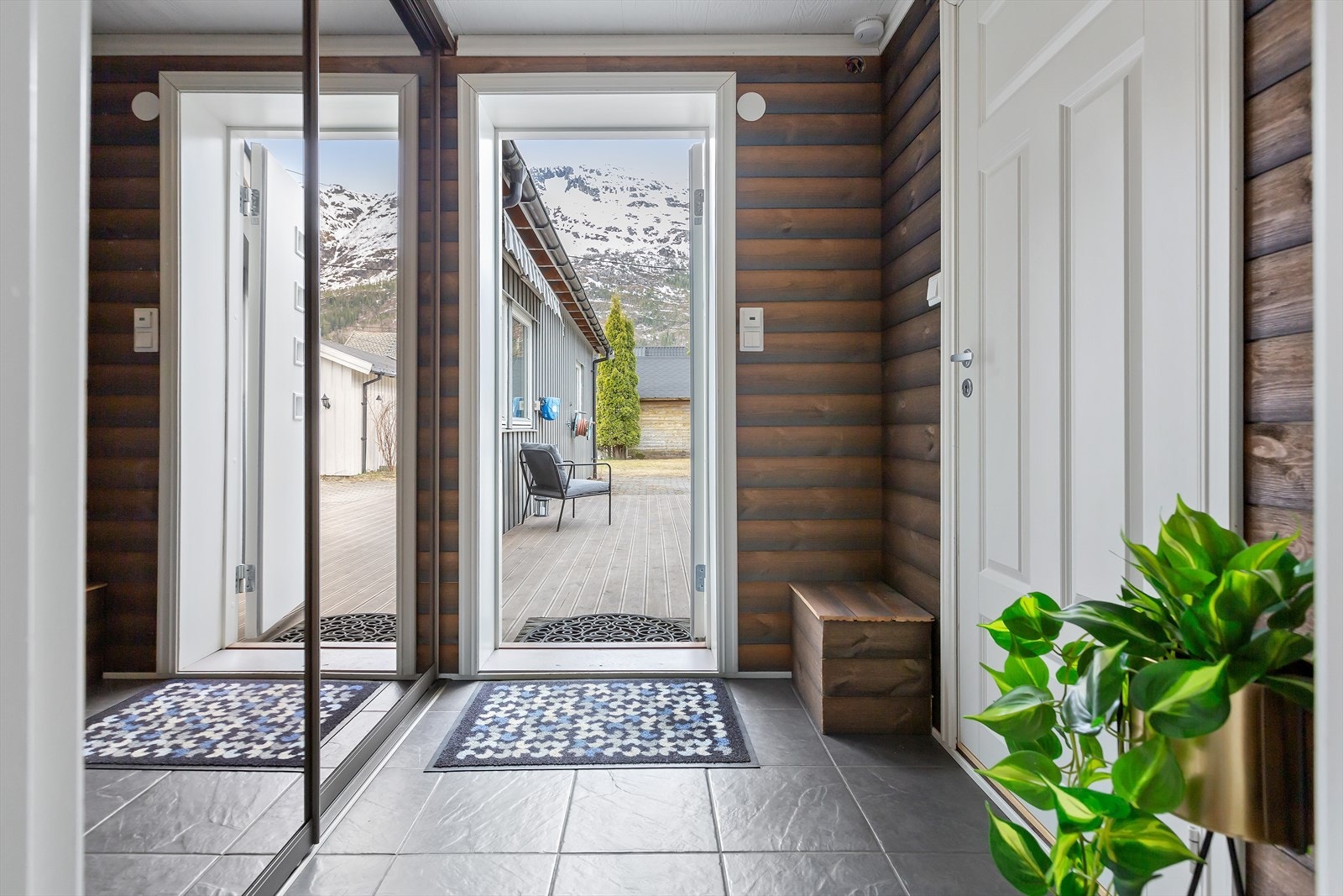 Praktisk gang med skyvedørsgarderobe til å henge fra seg klær og sko. Flislagt gulv og panel på veggene. Herfra er det inngang til stue og vaskerom. Galleribilde