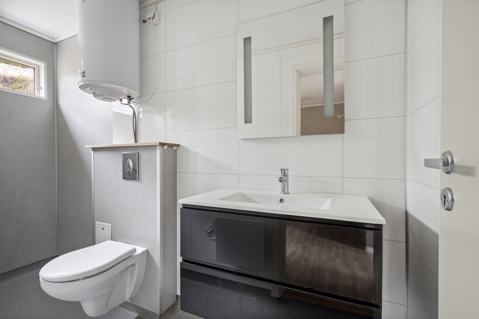 Pent nyoppusset bad med belegg på gulv og plater på vegger. Veggtoalett og moderne innredning. Galleribilde