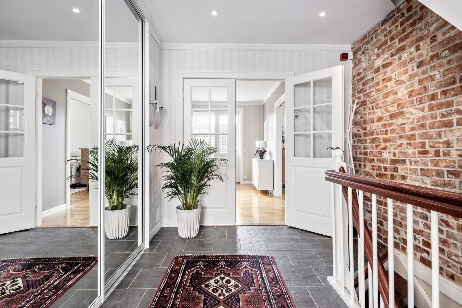 Velkommen inn i en romslig, flislagt entre med skyvedørsgarderobe Galleribilde
