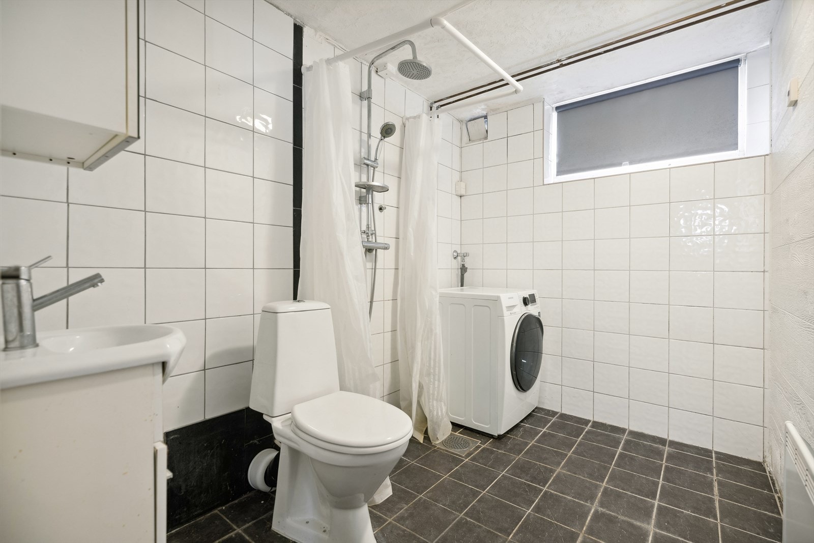 Romslig bad oppusset i 2009, med flislagte overflater oppvarmet med panelovn. Dette badet er utstyrt med dusj med forheng, gulvstående wc, servantinnredning med under- og overskap, samt opplegg og plass til vaskemaskin. Galleribilde