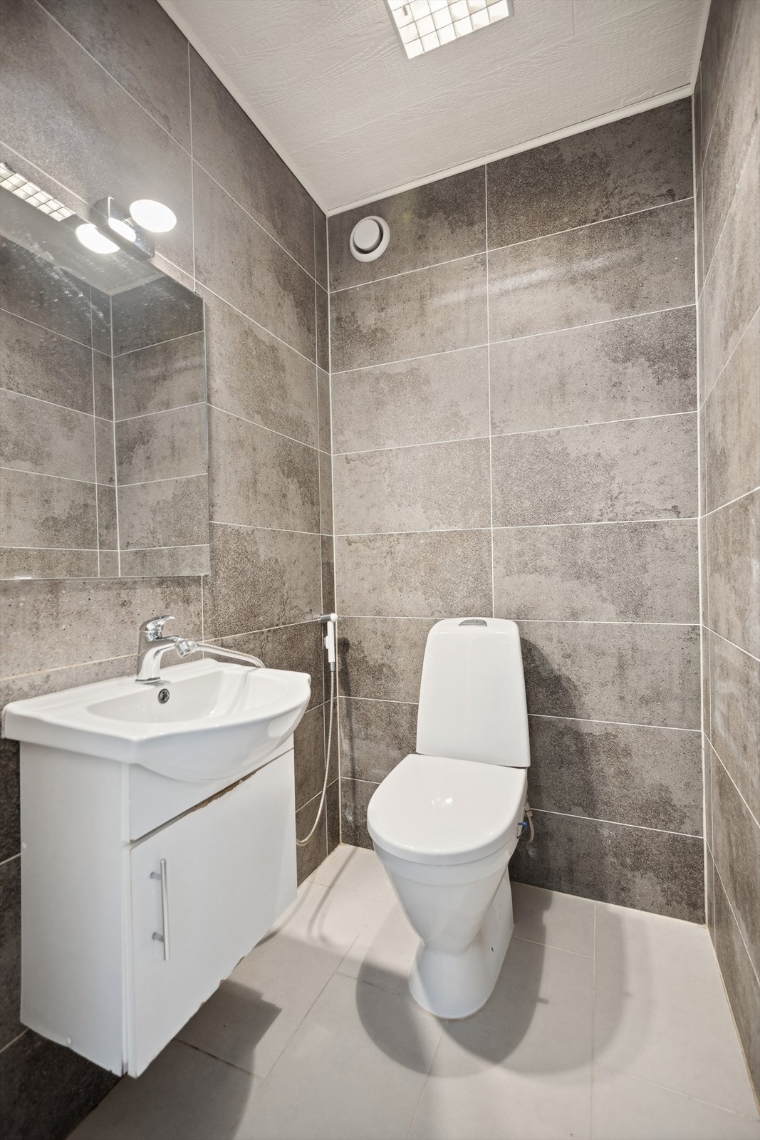 Flott flislagt gjestetoalett praktisk beliggende ved entréen. Rommet er utstyrt med gulvstående wc og servantinnredning med underskap. Galleribilde