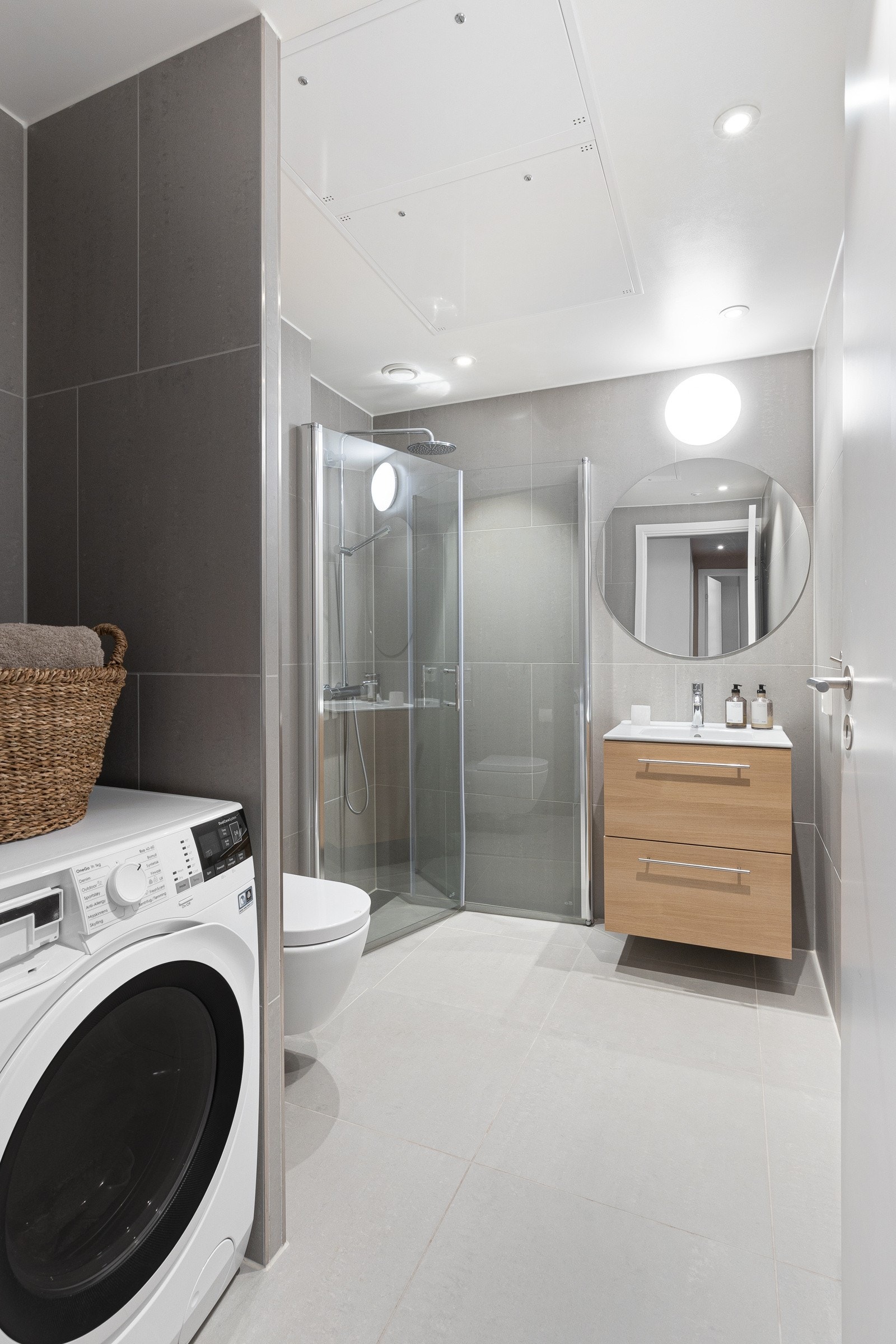 Badet er utstyrt med vegghengt toalett, dusjhjørne med deilig regnfallsdusj og håndholdt dusj. Videre er det servantskap med innredning og opplegg for vaskemaskin. Galleribilde