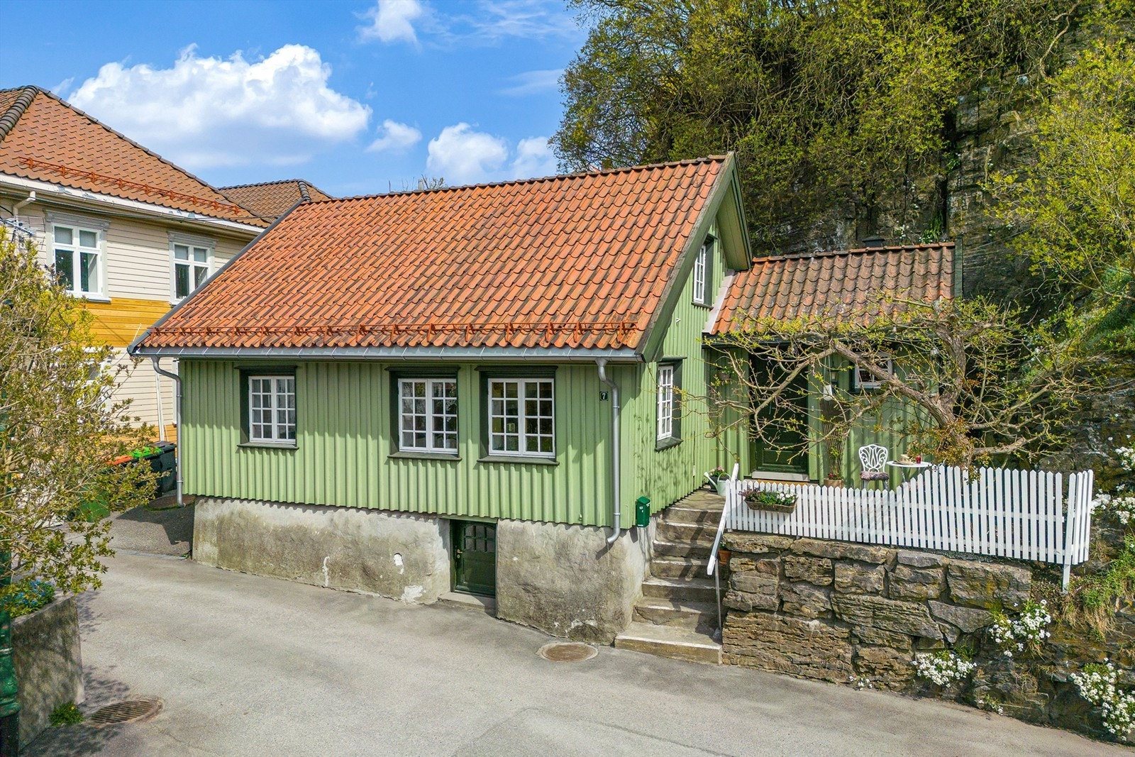 Store syrinbusker dekker berget bak huset. Galleribilde