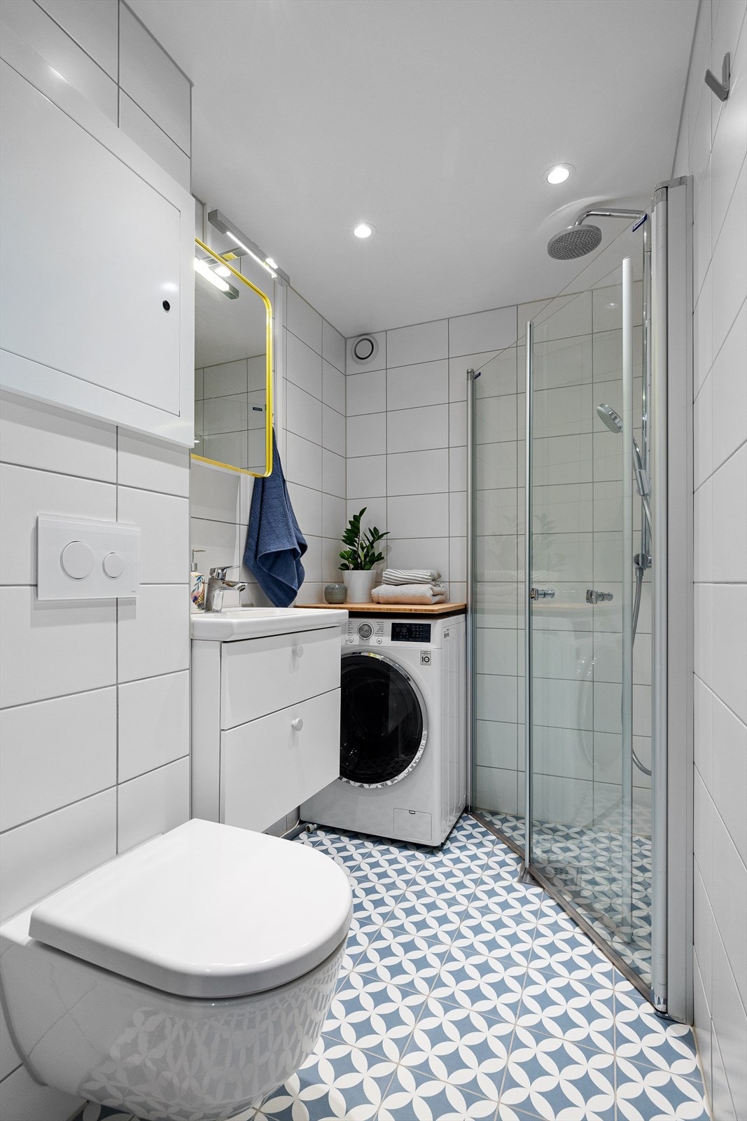 Pent flislagt og lyst baderom med dusjhjørne og opplegg for vaskemaskin Galleribilde