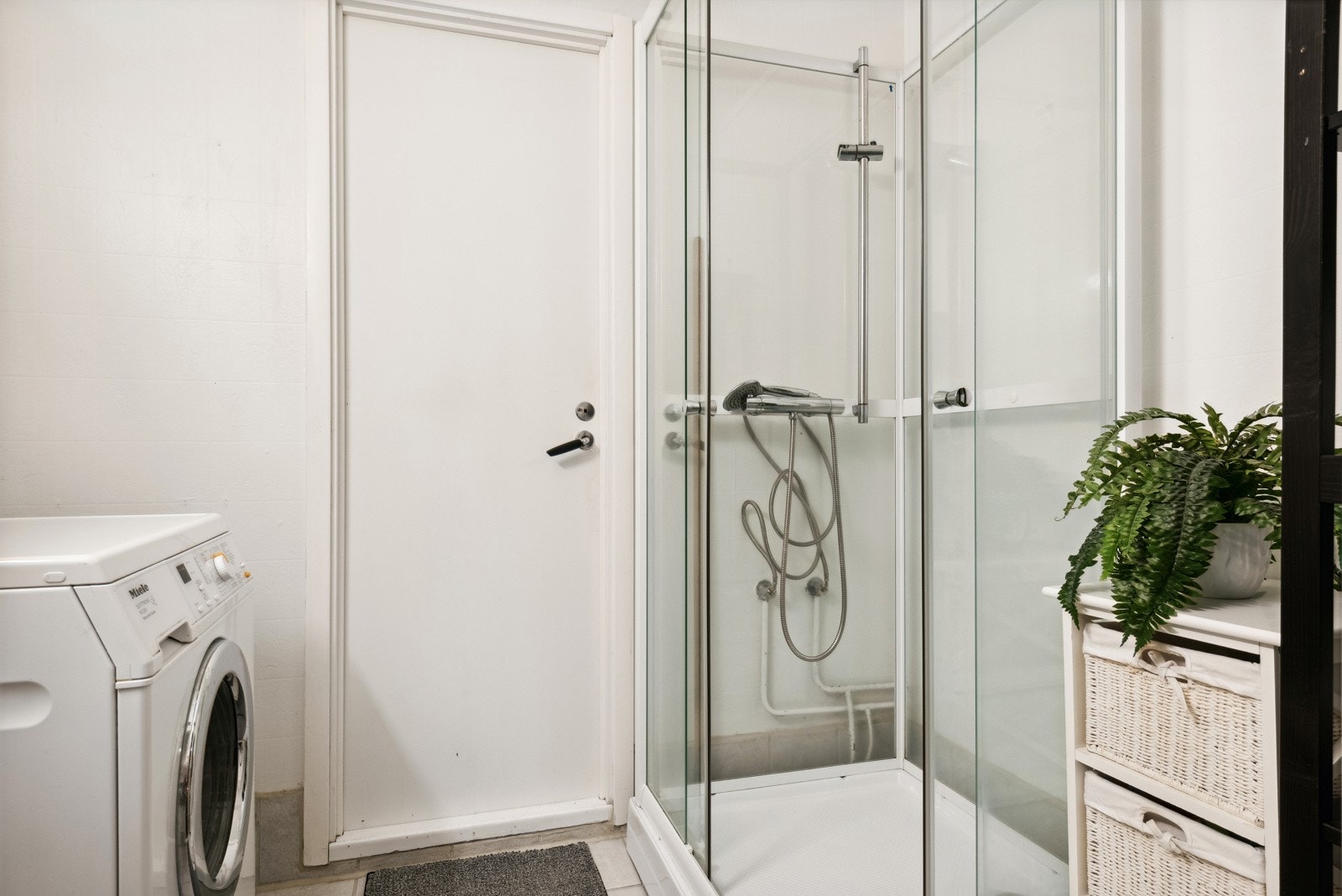 Eldre bad/vaskerom med fliser på gulv, vinyltapet på vegger og slett malt tak. Galleribilde