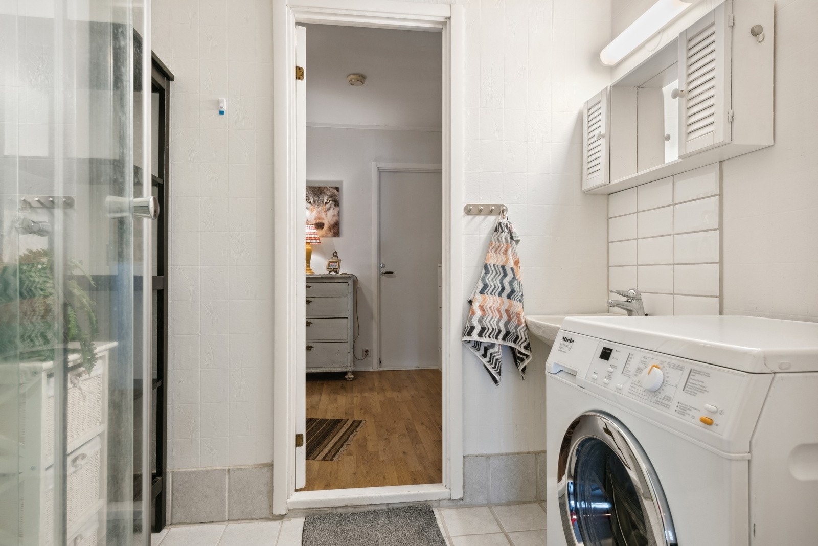 Badet inneholder porselensvask, overskap med speil og overlys, dusjkabinett og opplegg for vaskemaskin. Galleribilde