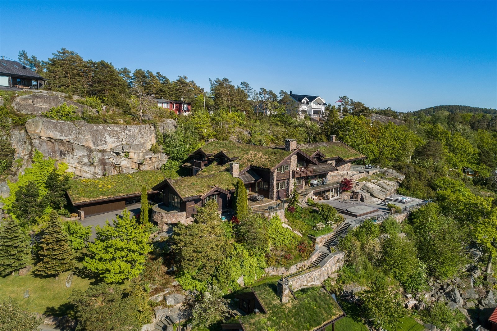 Med villmarkspanel, natursteinsmurer og torvtak glir den enorme eiendommen sømløst inn i landskapet. Galleribilde