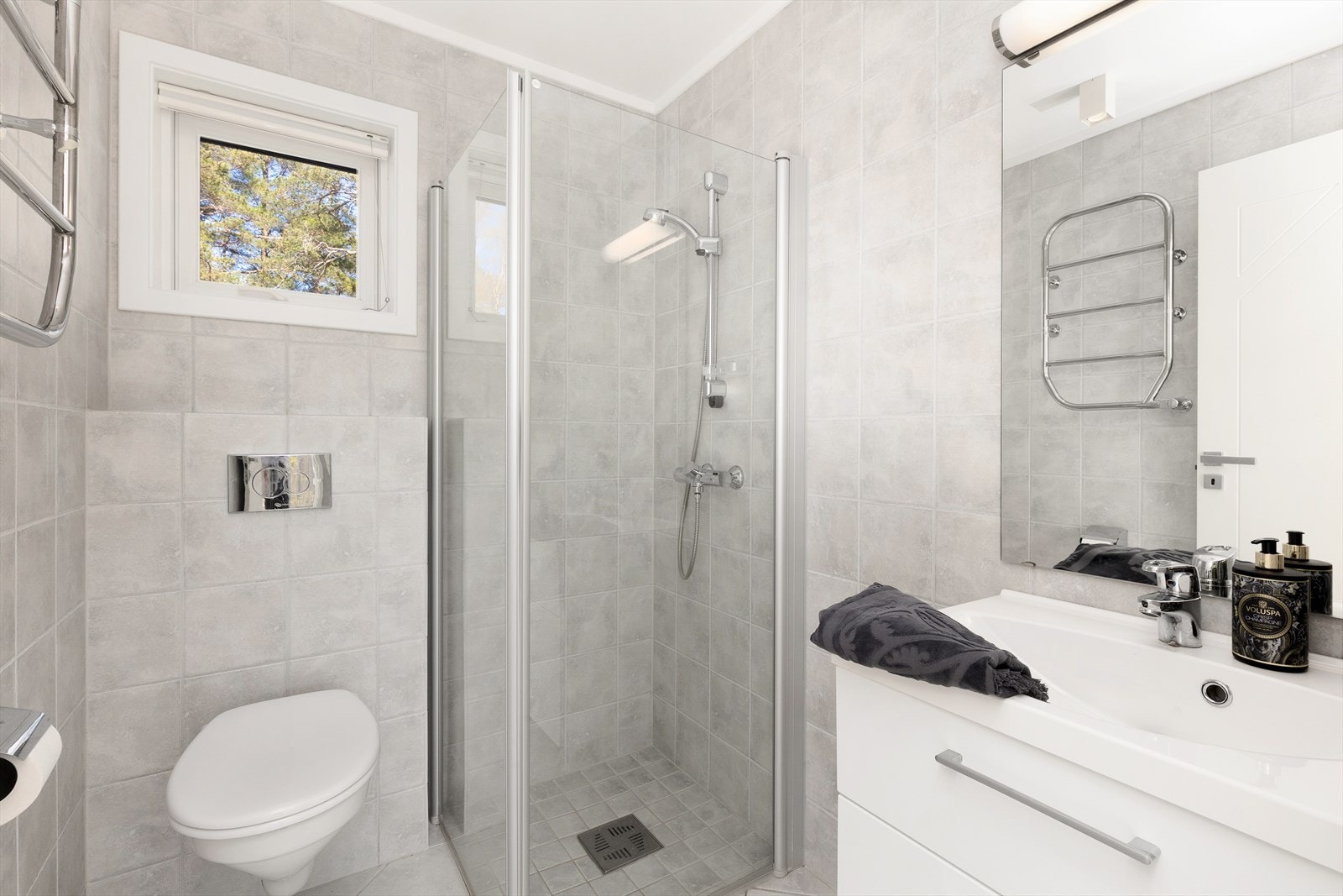 Badet i gjestedelen har veggmontert toalett, dusjhjørne og hvit innredning. Galleribilde