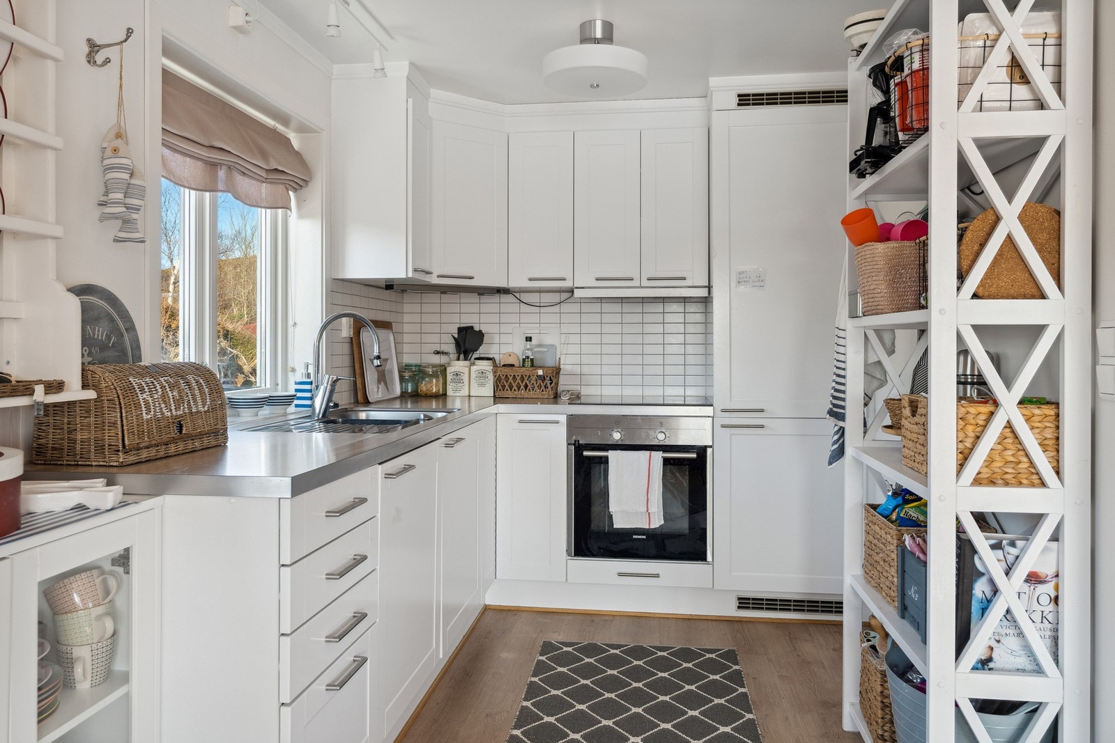 Kjøkkeninnredning med profilerte hvite fronter og fliser på vegg. Galleribilde