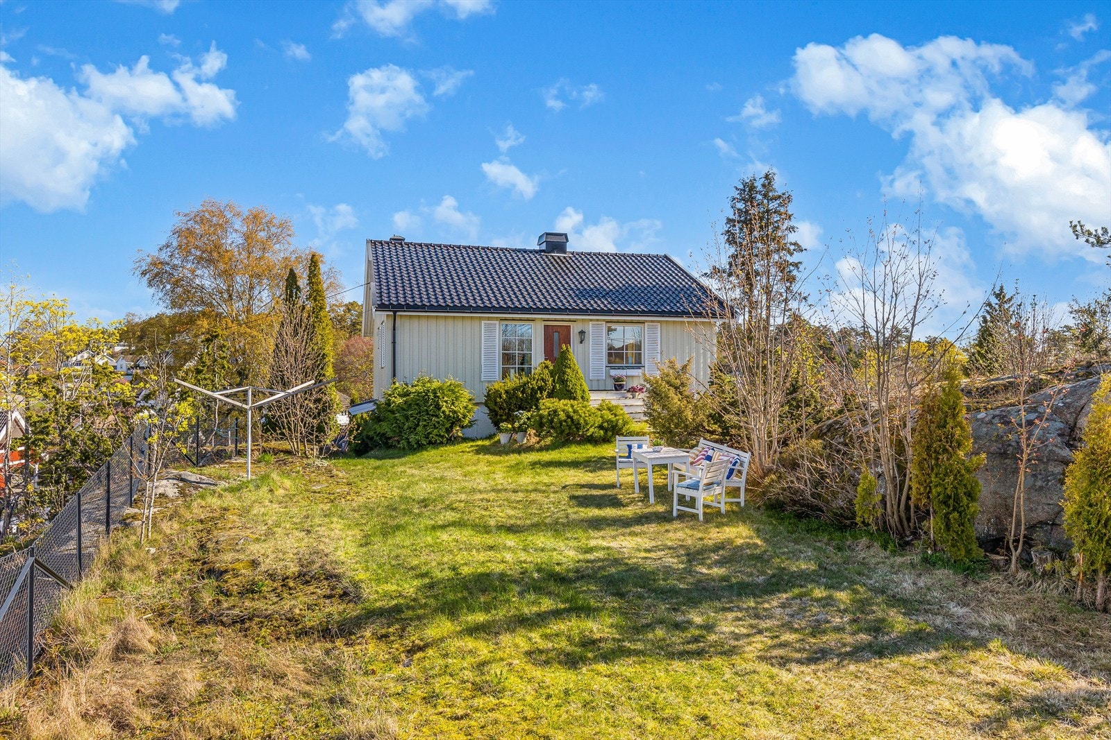 Dette er en pent opparbeidet naturtomt med plen, frodige beplantninger, trær og fjell i dagen. Galleribilde
