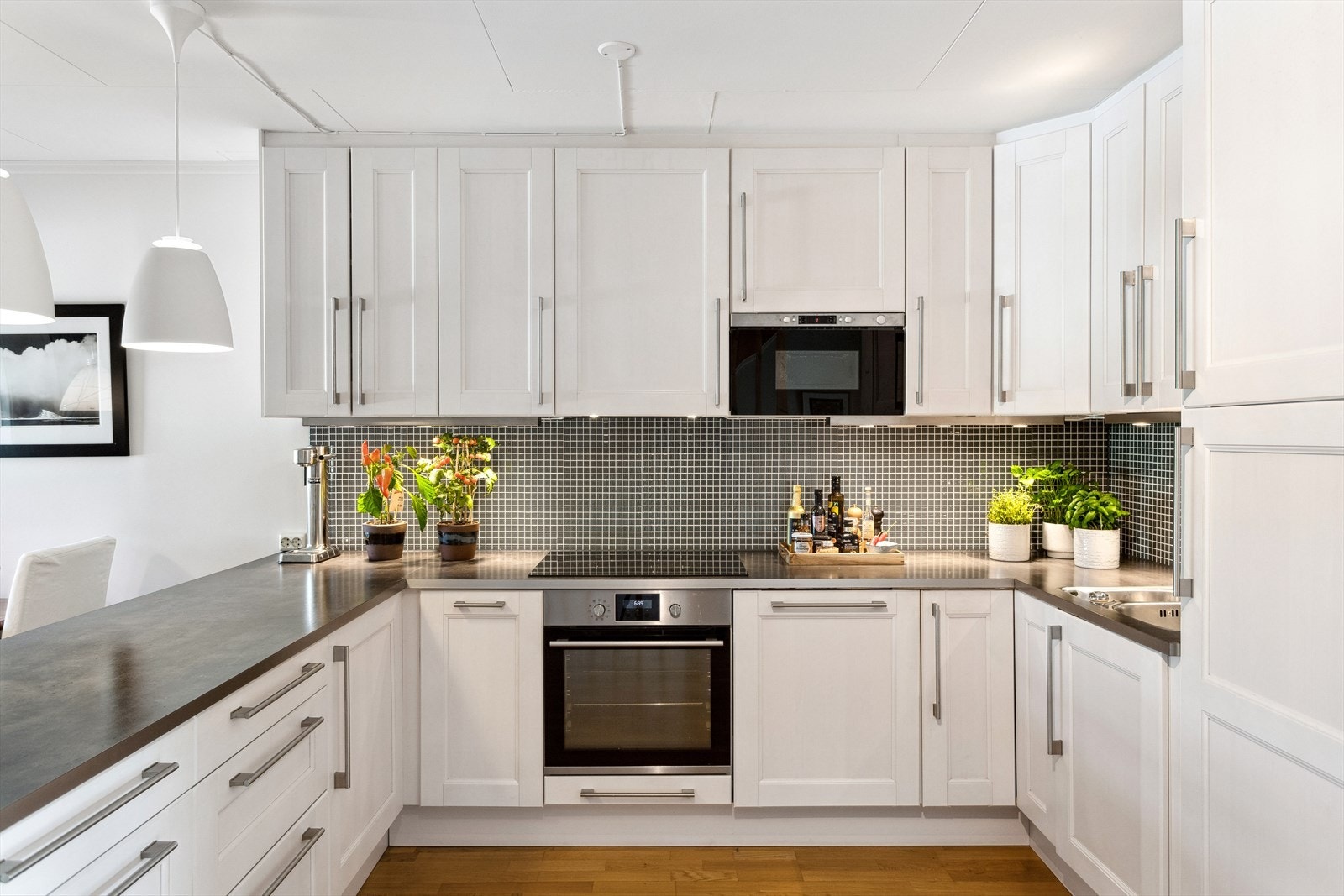 IKEA-Kjøkkeninnredning fra 2010 med hvite malte profilerte fronter, laminat benkeplate med underlimt oppvaskkum og nedfelt induksjon koketopp. Galleribilde