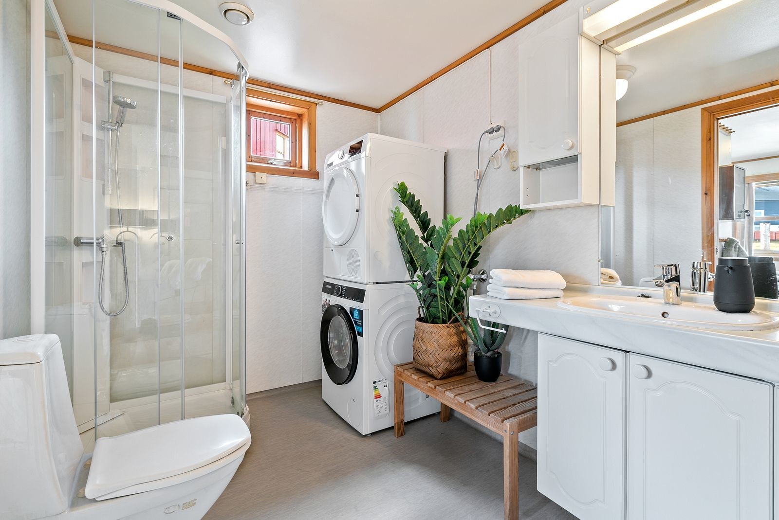 Badet er utstyrt med dusjkabinett, toalett, servant på skapinnredning og opplegg for vaskemaskin. Galleribilde