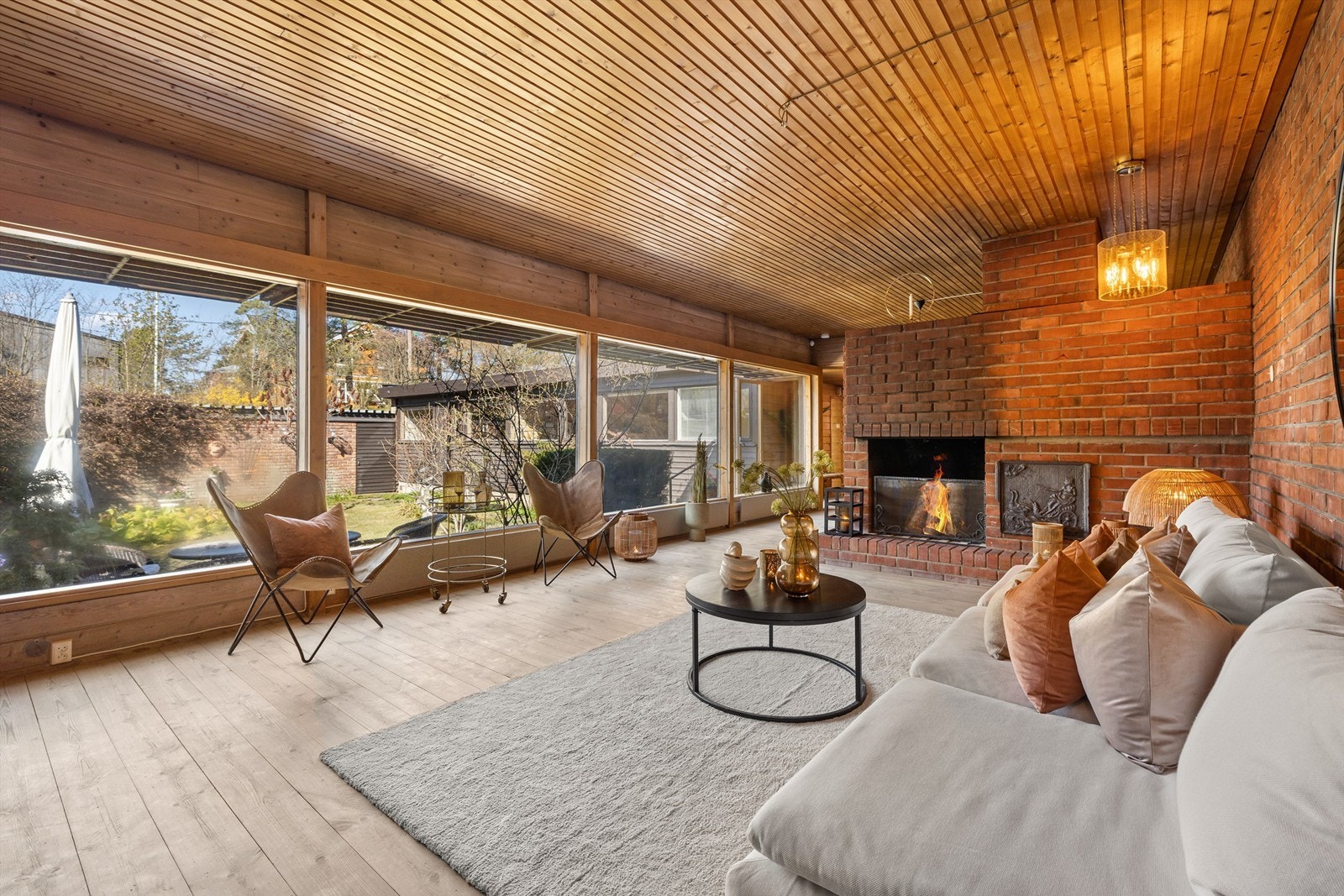 Stue med peis og store vinduer som gir fint utsyn til atriet Galleribilde