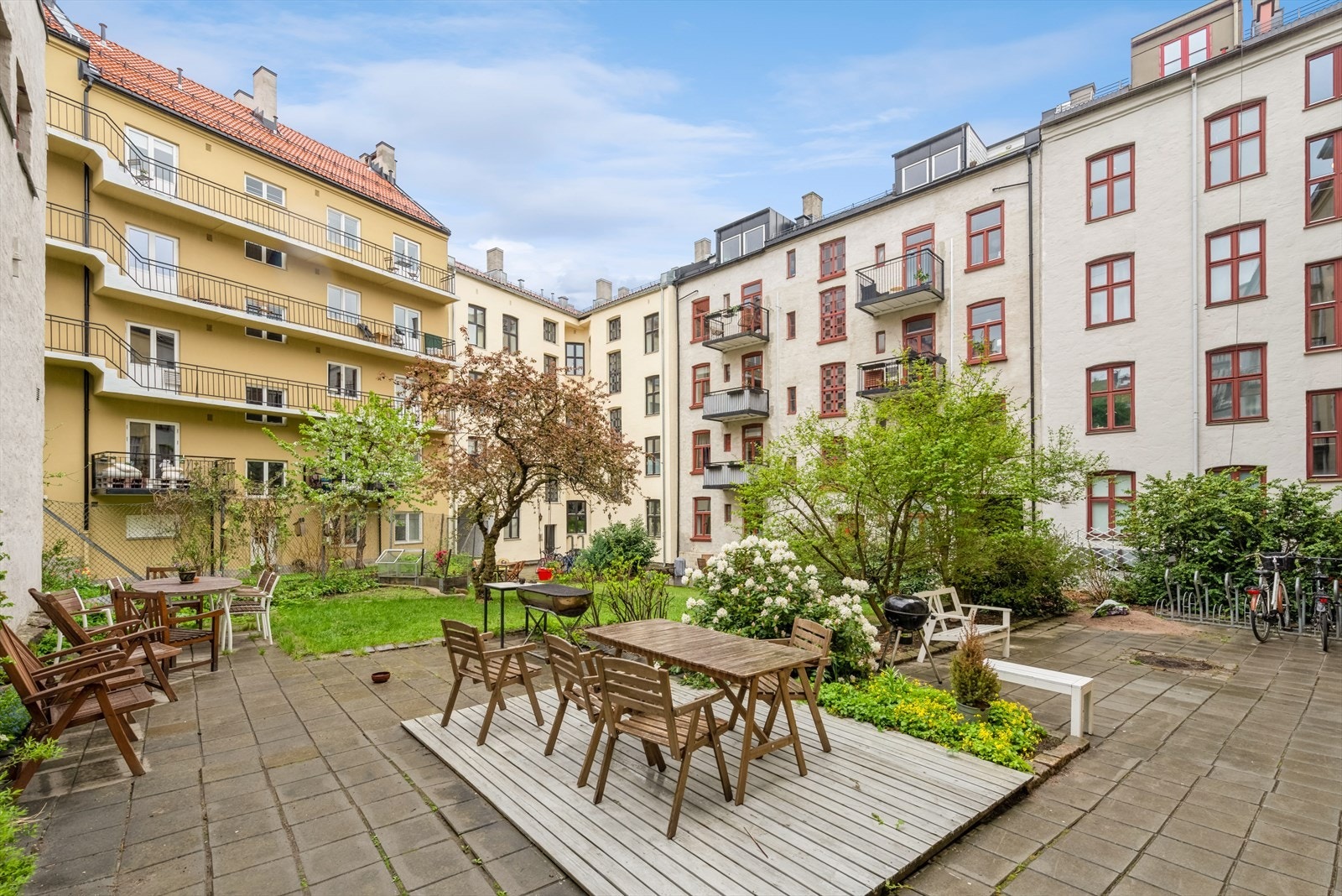 Stor, felles bakgård som er solfylt og frodig. Galleribilde