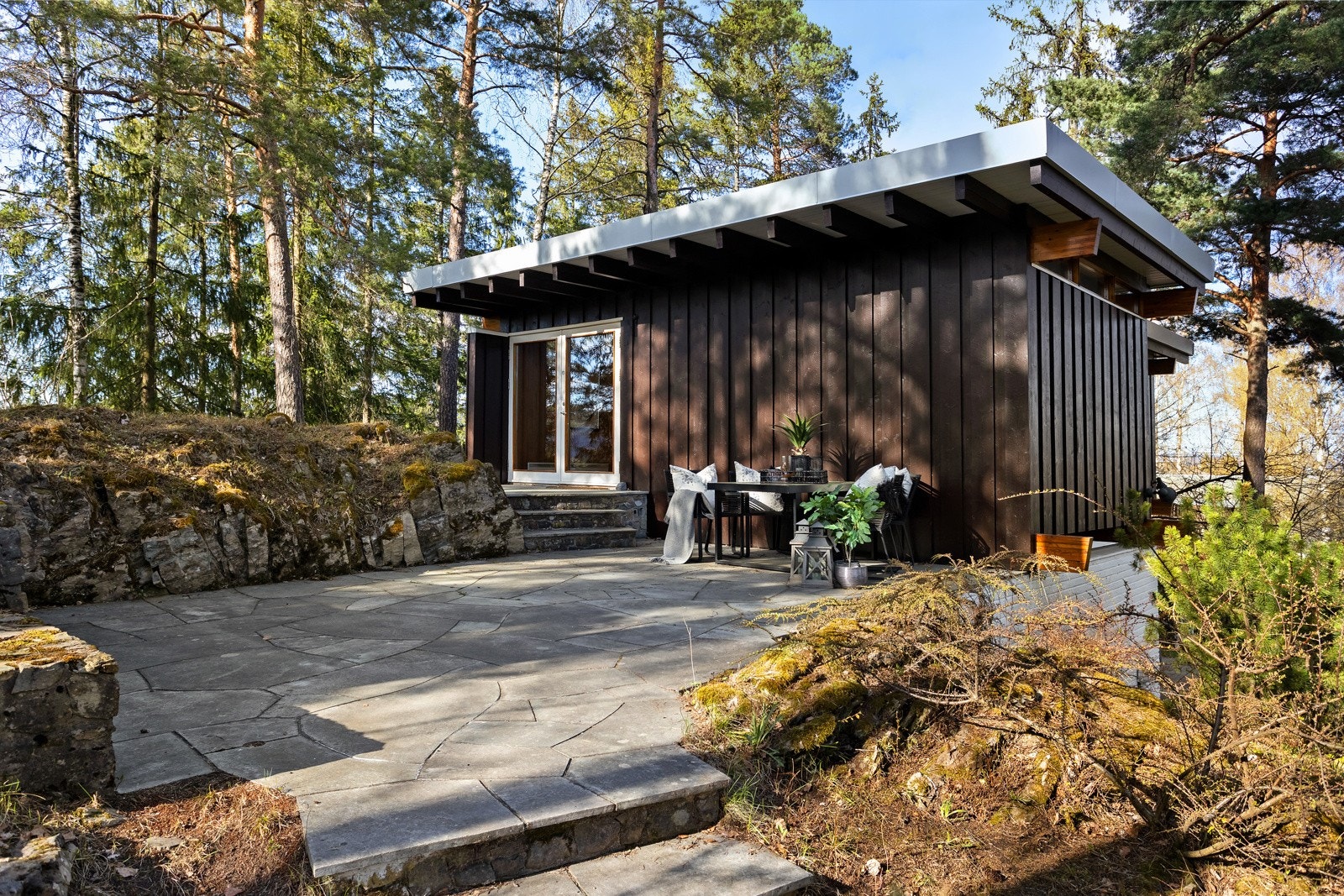 En god miks av solinnfall mot syd på den hellelagte uteplassen. Svalt i skyggen av trærne på varme dager, med mulighet til å sitte i sol på samme sted. Galleribilde